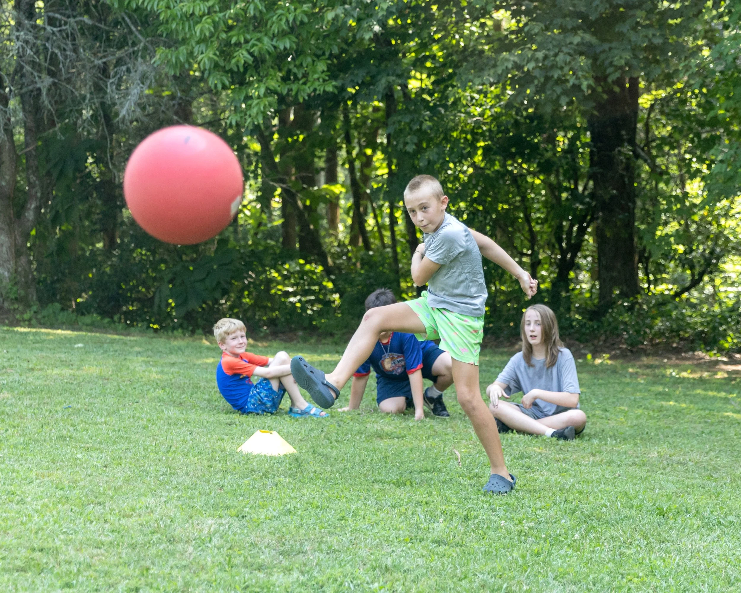 A boy at summer camp kicks a ball at Camp Arrowhead overnight camp