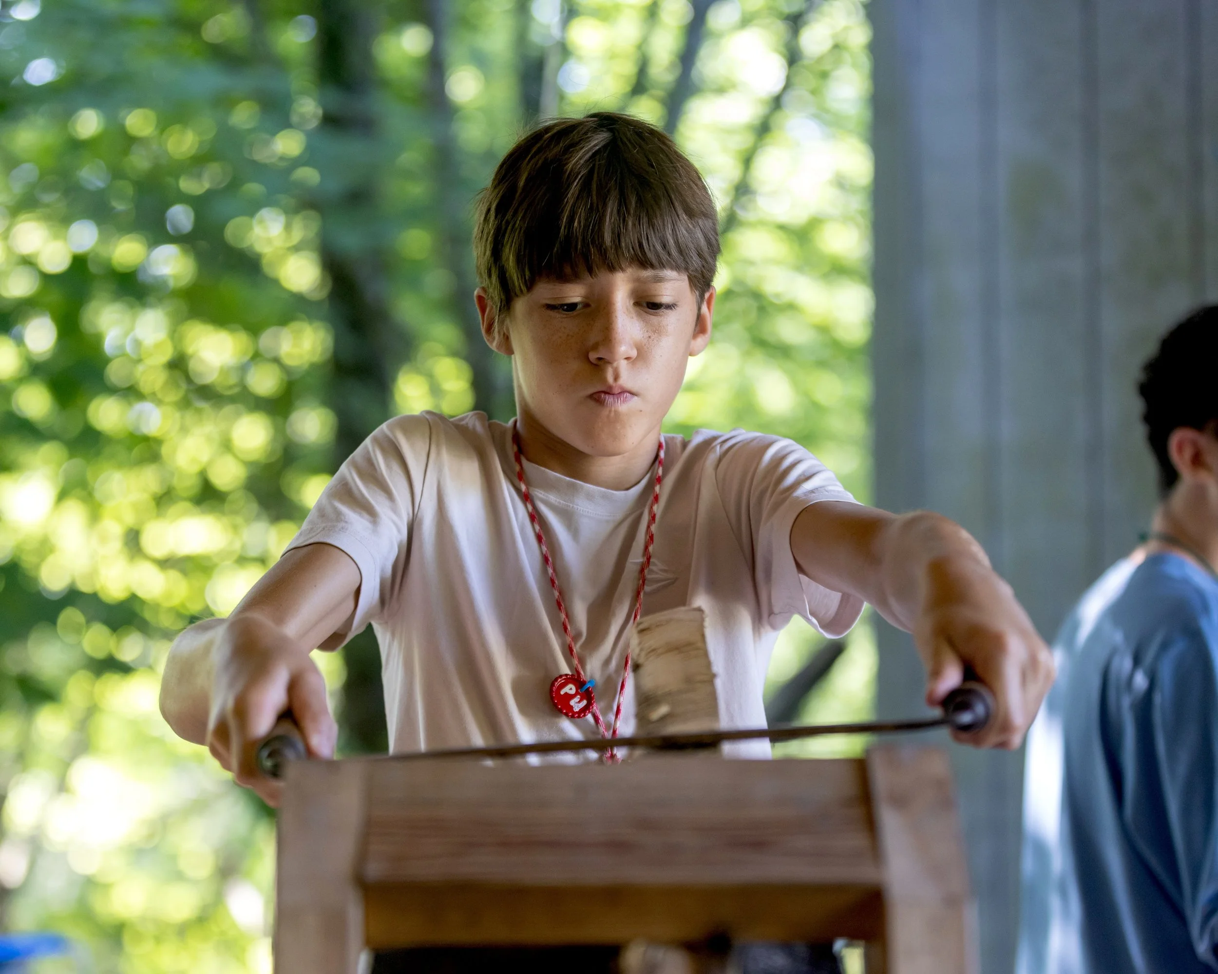 Arrowhead sleep away camper using a drawknife in the bushcraft program.