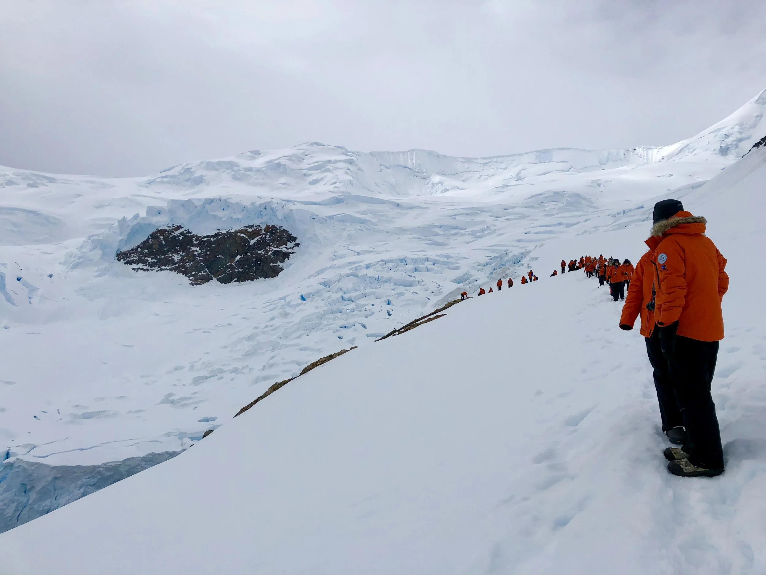 Passengers of the National Geographic Orion climb a mountain in Antarctica.