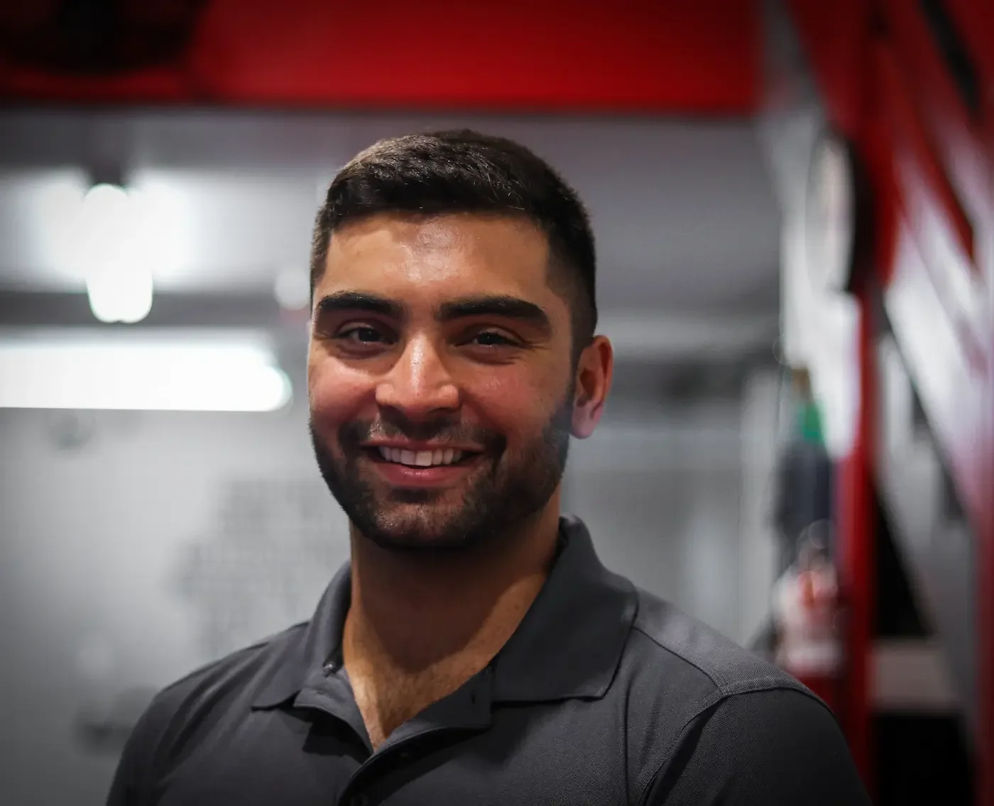 Smiling man in dark gray polo shirt in gym or fitness center