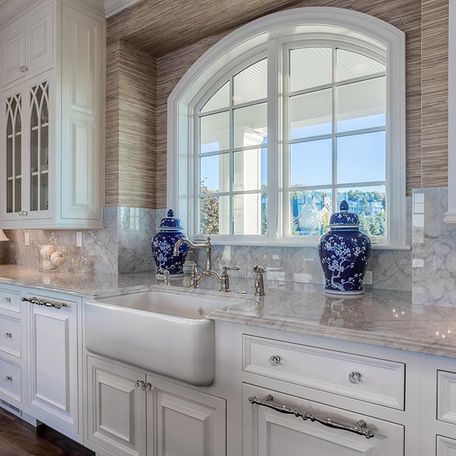 This delightful grass-papered Bay Harbor home is stacked with custom maple cabinets, satin nickel faucets, 6-inch crown molding, carrara marble, solid black walnut flooring, OG nosing, stainless steel appliances, arched Kolbe windows, a Kohler farmho