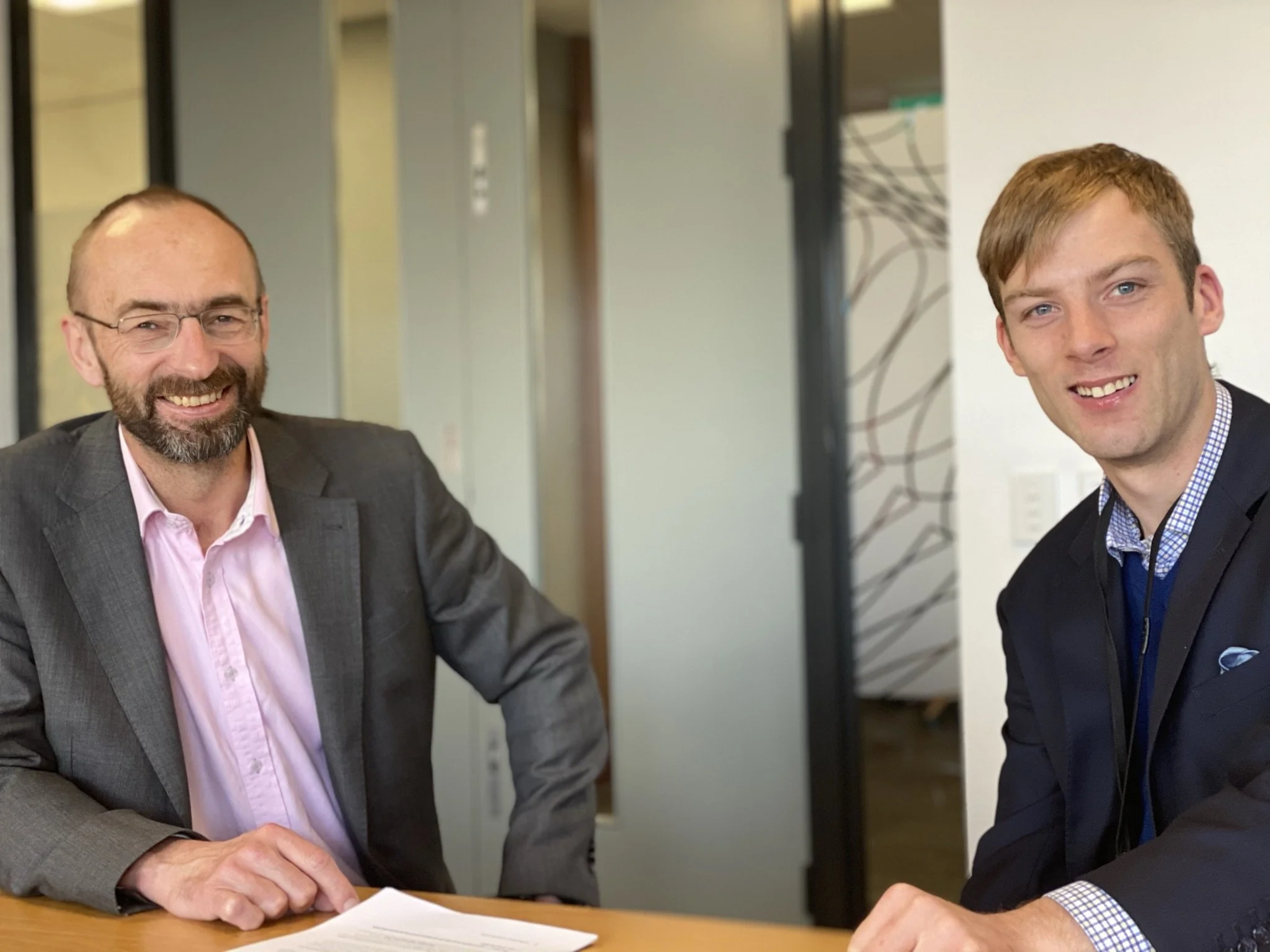Reserve Bank of New Zealand meeting room with employees seated left to right X and Shaun Markham, Wellington.