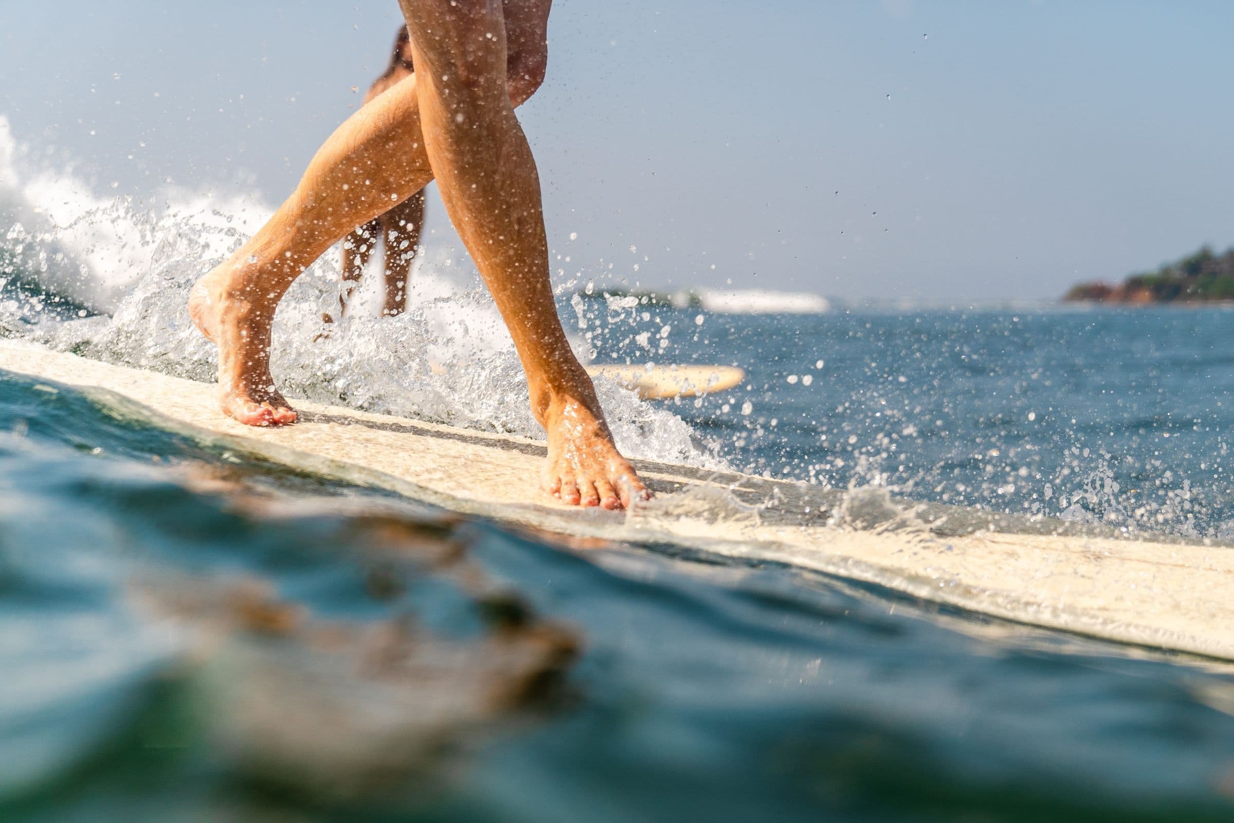 Layback surfer riding a clean wave with the Sri Lankan coastline visible