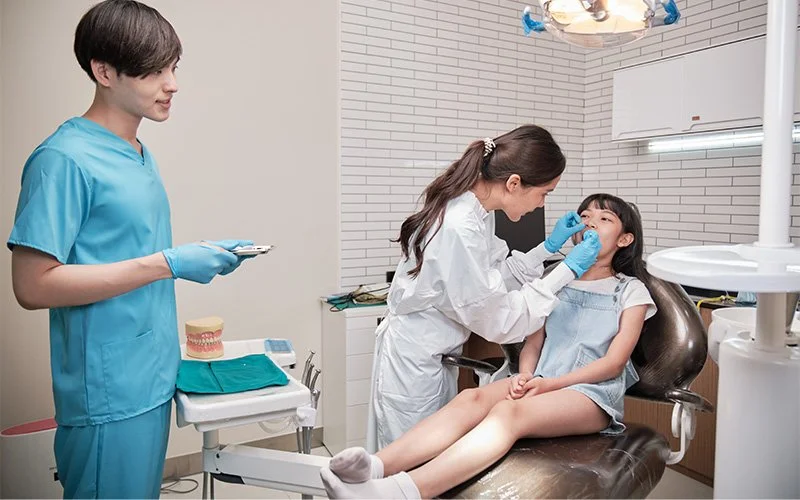 Child receiving dental check-up from professionals.