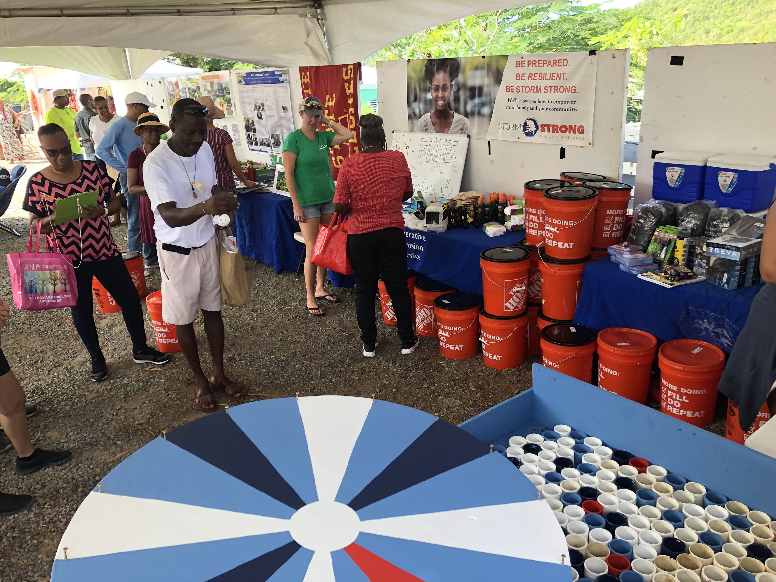  Community Foundation of the Virgin Islands (CFVI) Junior Angels Program Coordinator Caitlin Goodwin talks with a community member while others participate in carnival games for the supply distribution CTP at the 2019 St. Thomas &amp; St. John Agricu