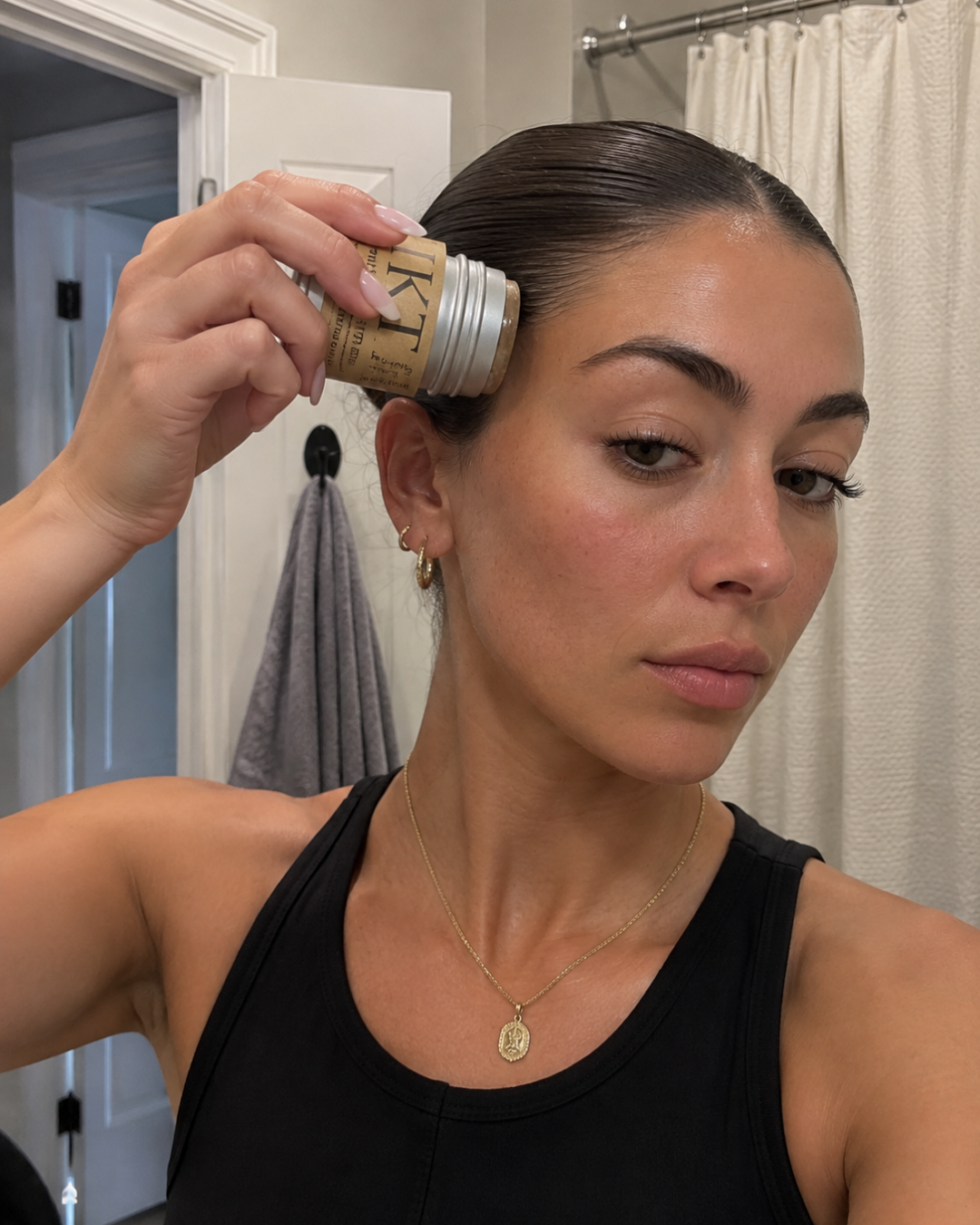 Woman applying a wax stick on her hair for the viral TikTok beauty trend.
