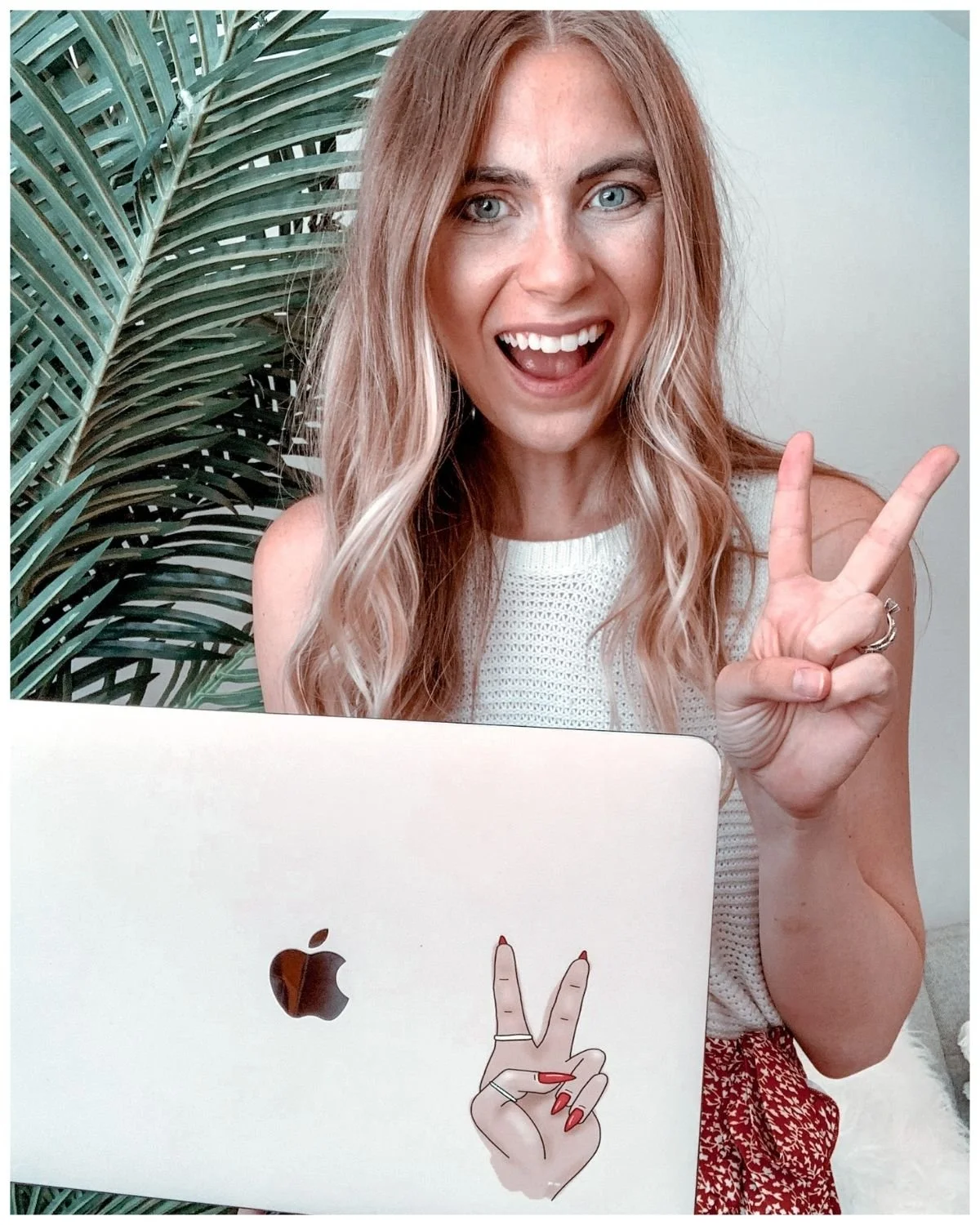 woman holding up peace sign and laptop