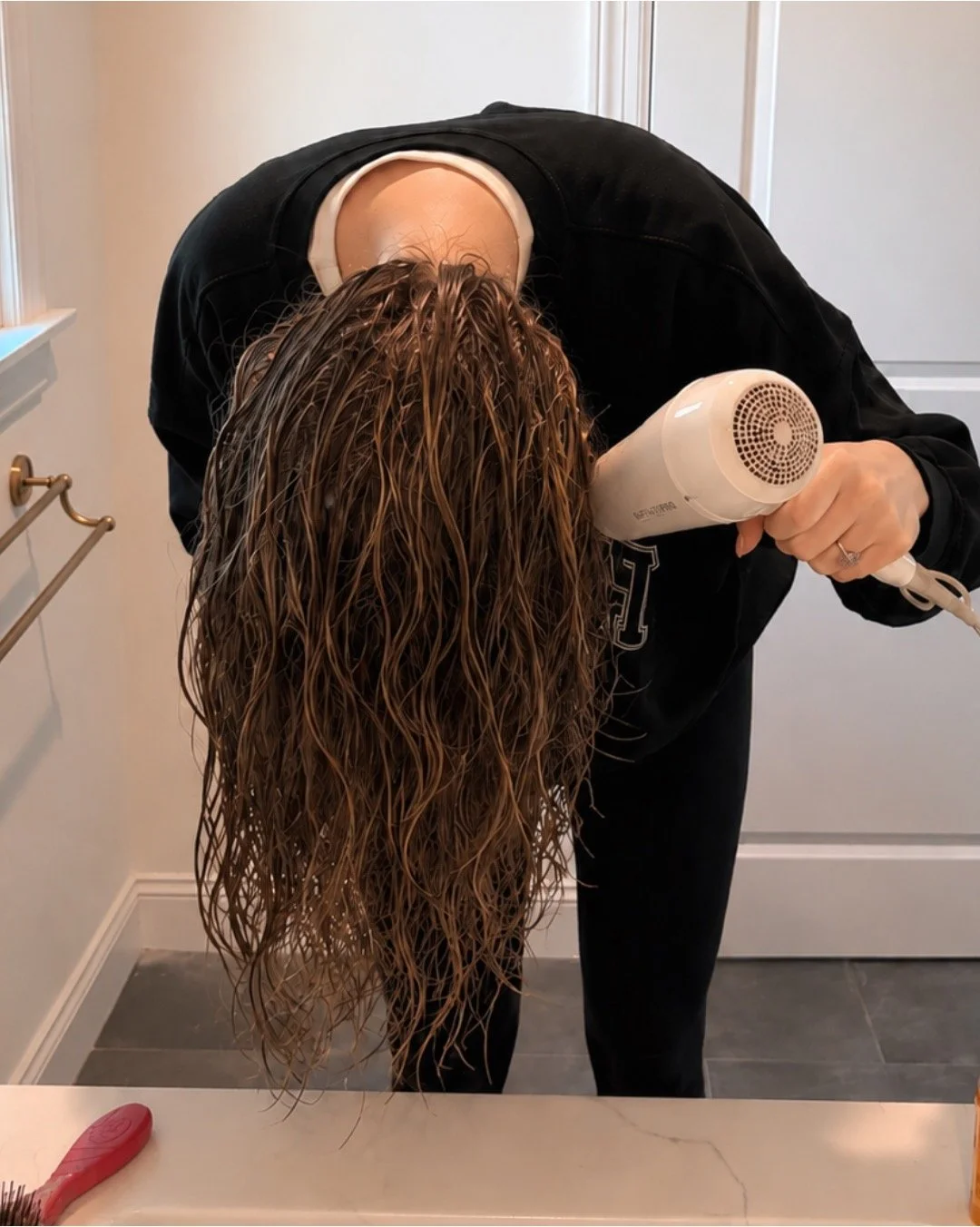 woman bow drying wet hair upside down in her bathroom
