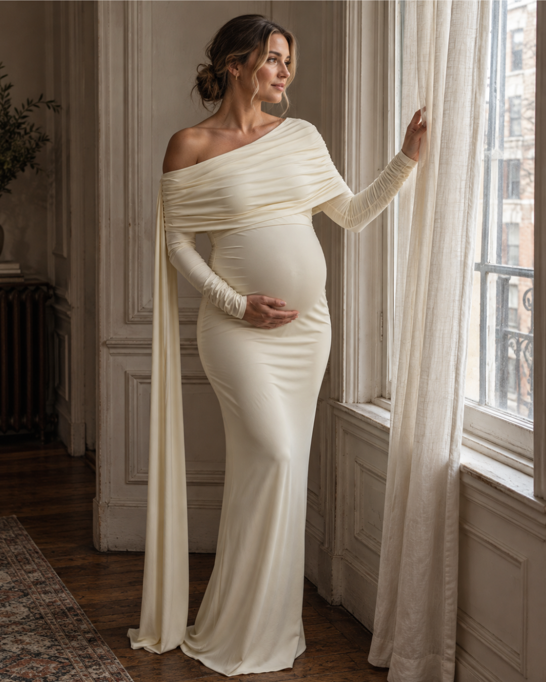 Cream one-shoulder maternity dress beside window