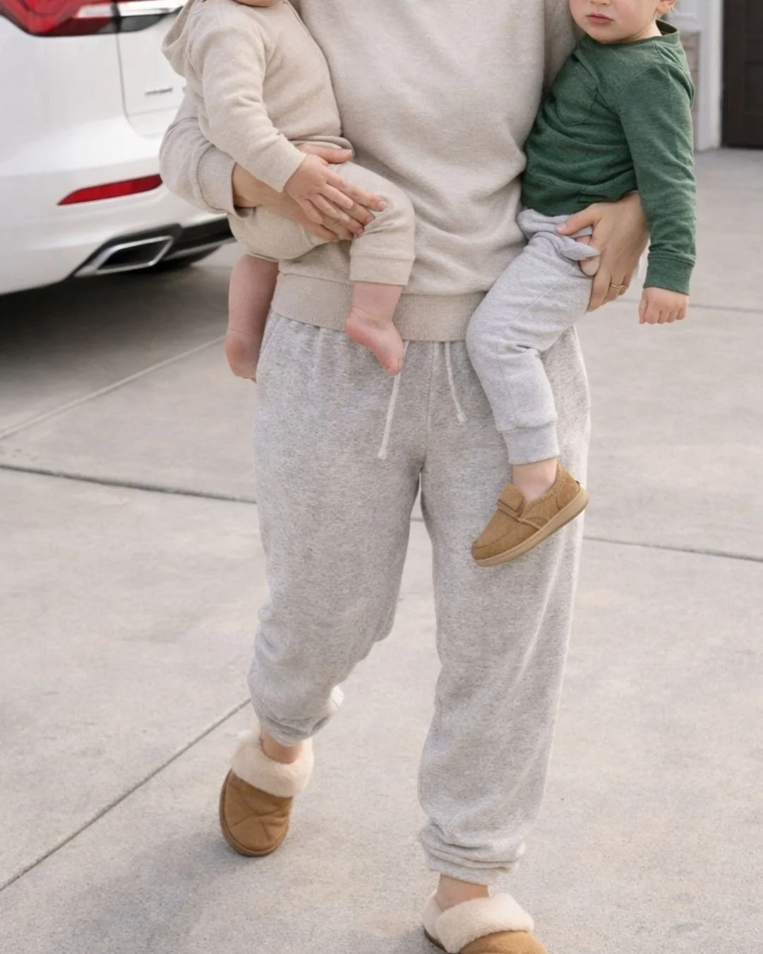woman holding two kids in driveway