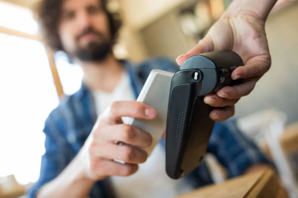 Cafe owner taking a contactless card payment after the card surcharge ban in Australia