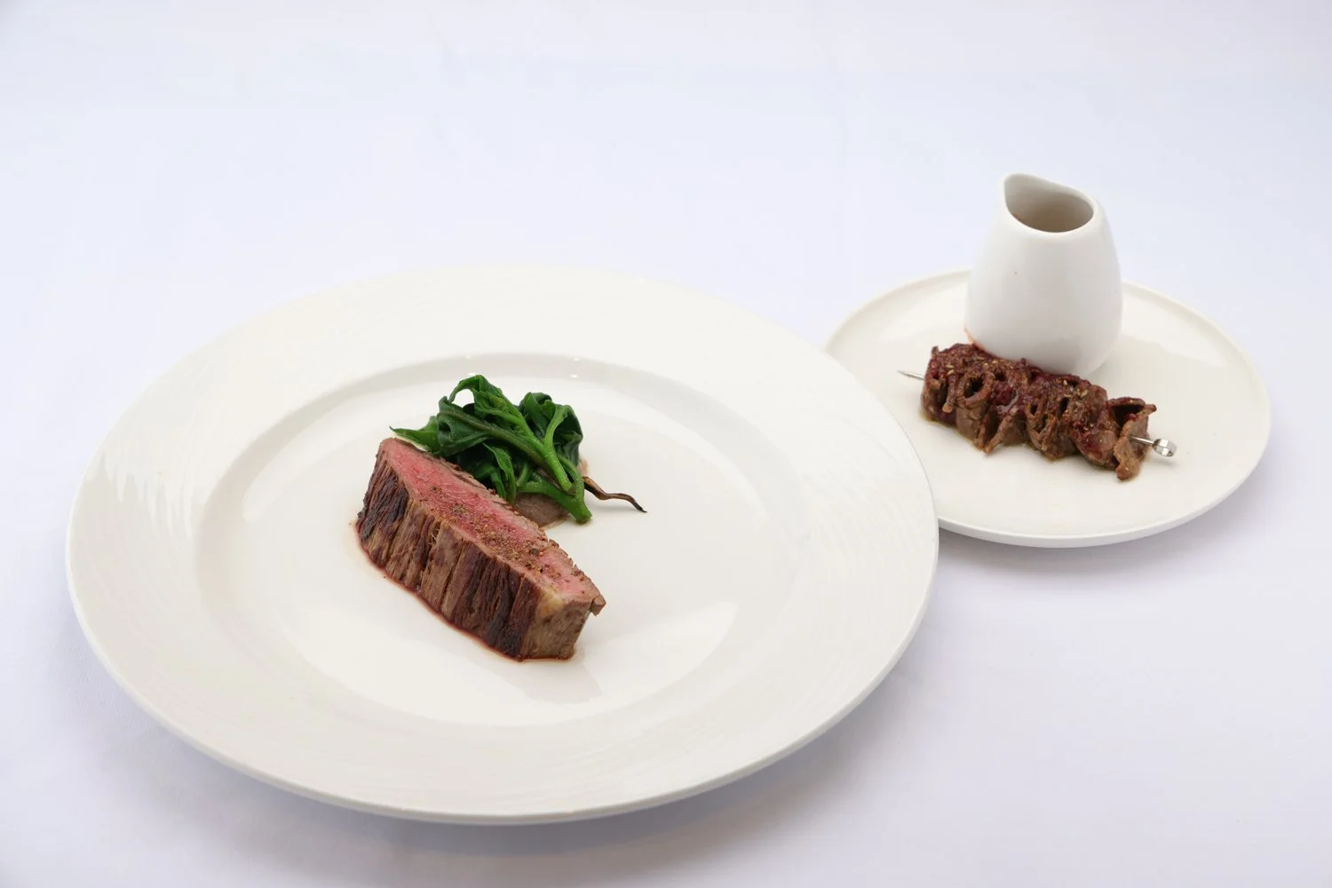 beef flank with eggplant puree, candied eggplant, warragal greens, and a raspberry-glazed beef skewer
