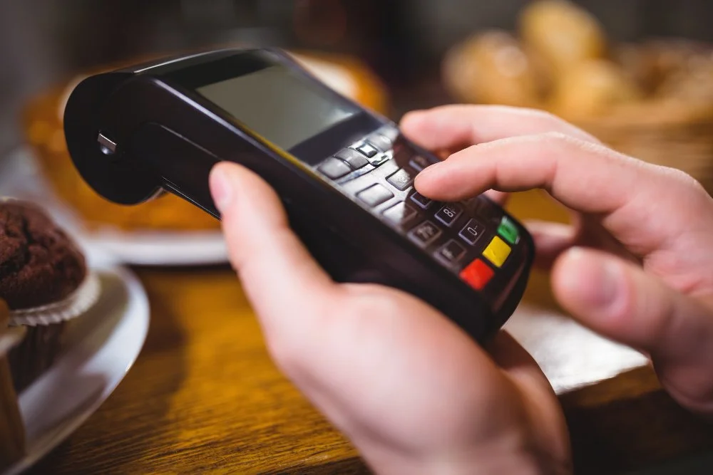 Cafe owner taking a contactless card payment after the card surcharge ban in Australia