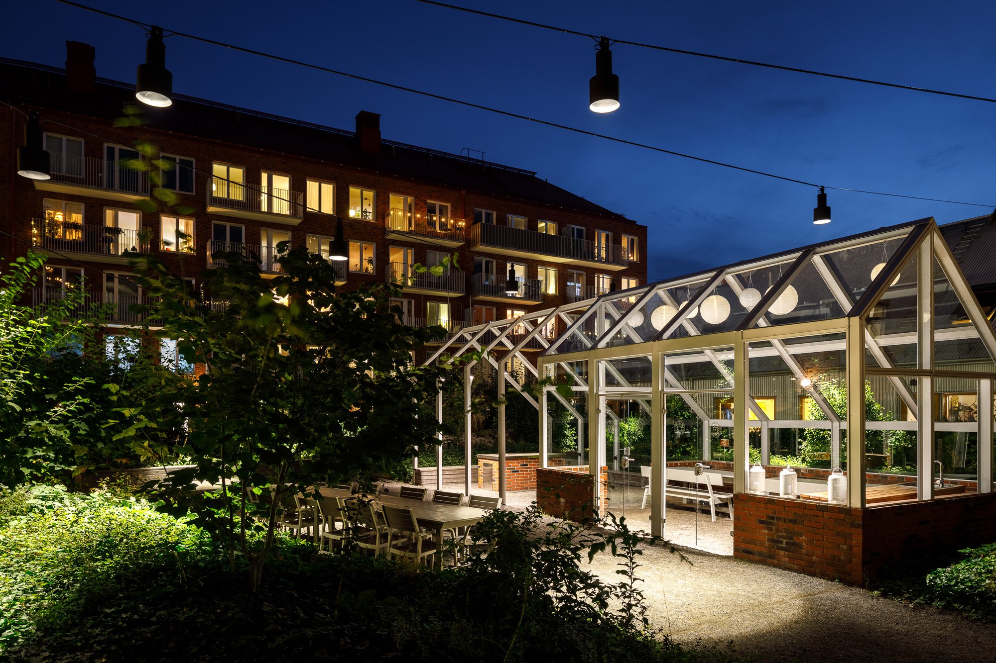 Upplyst orangeri på vacker bakgård i Sundbyberg kvällstid