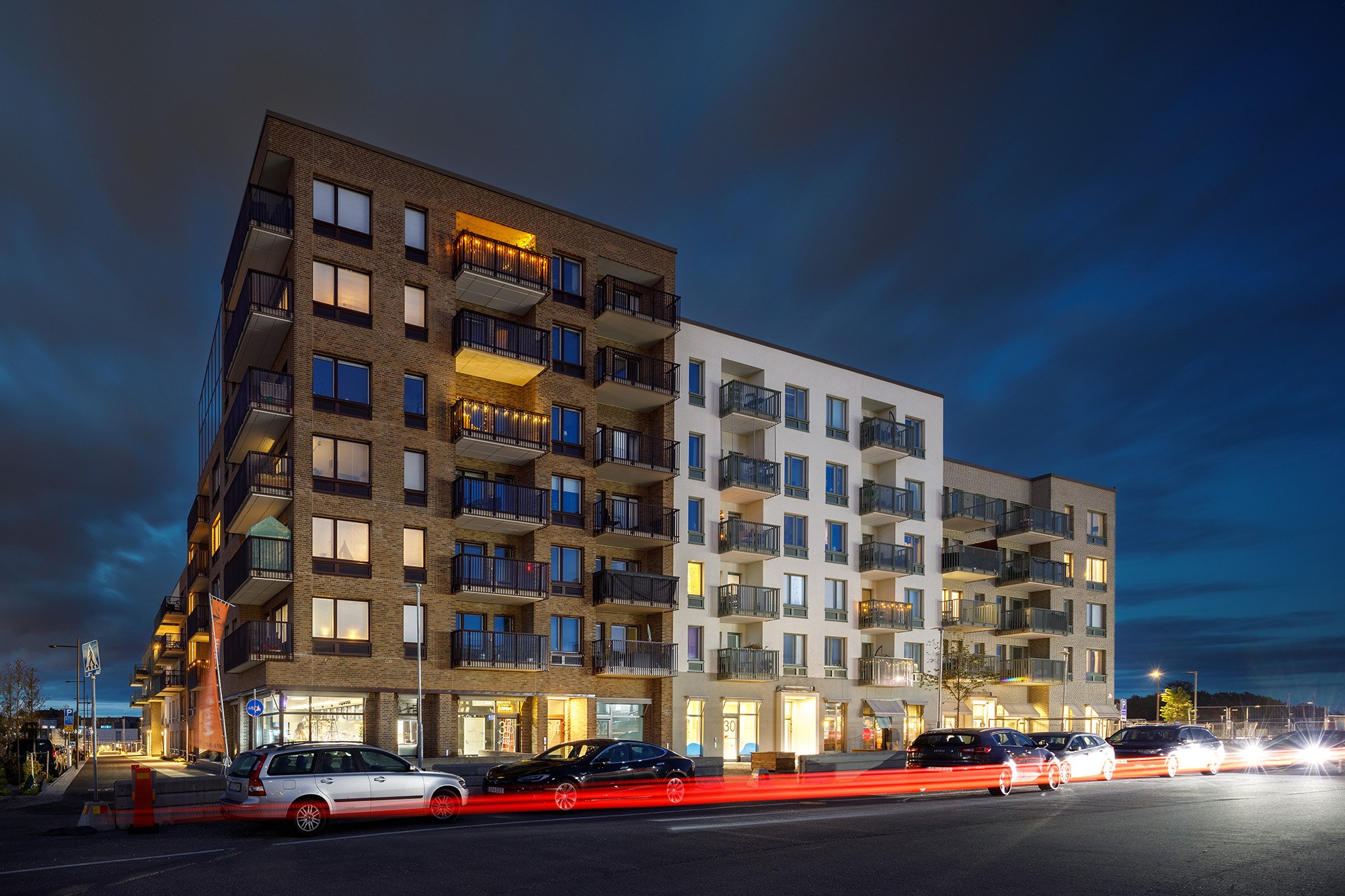 Täby Turf nybyggt bostadskvarter med mörkblå kvällshimmel och billyktor i förgrunden