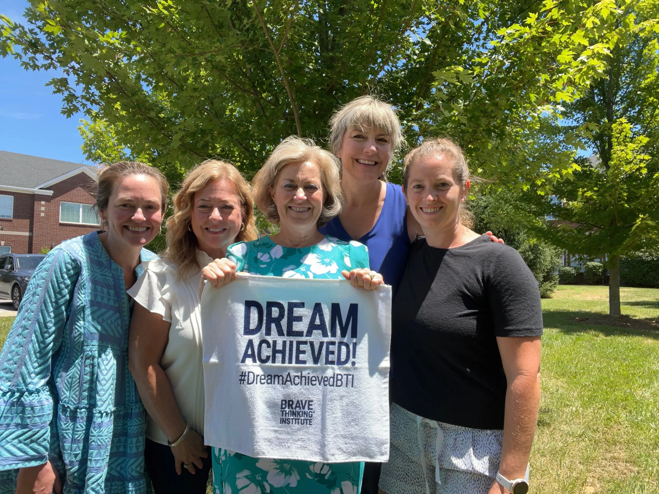 Photo of the IIM team outside holding a Dream Achieved banner.