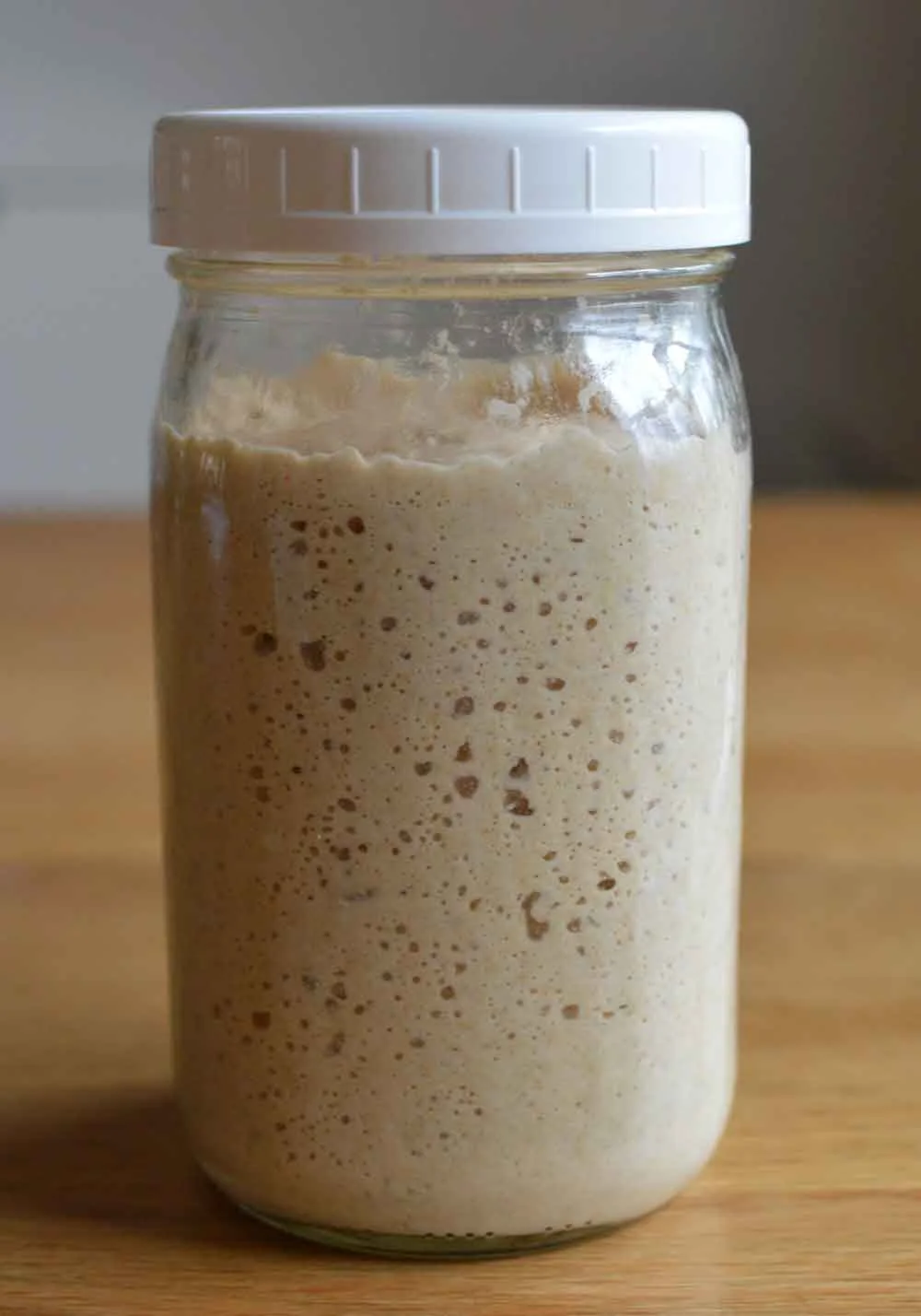 A jar filled with sourdough leaven that is bubbly and ready for use.