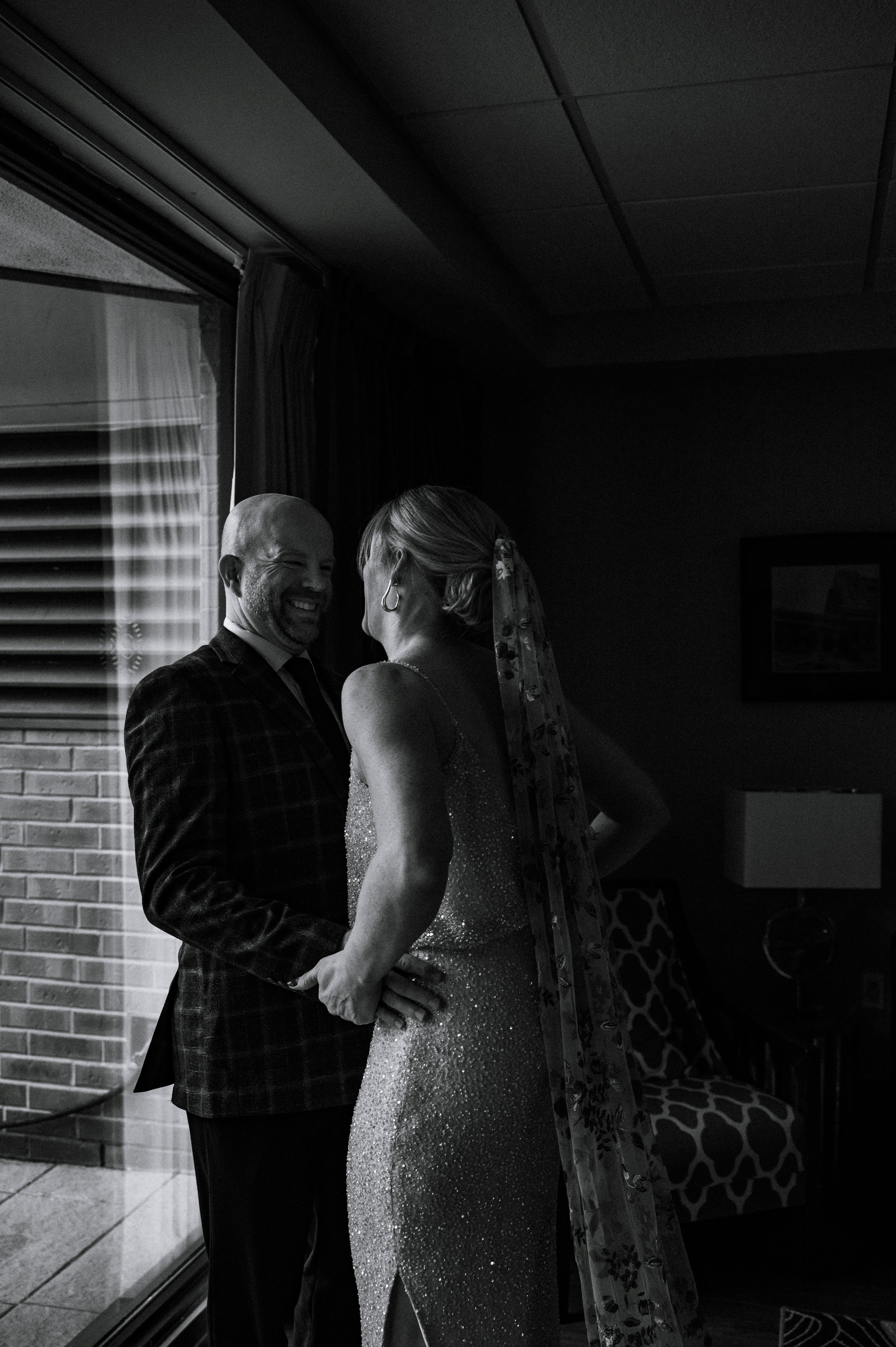 A classic black and white image of a bride and groom during their first look. They just saw each other and they're laughing together with excited, happy nerves during a wedding in Hamilton, Ontario.