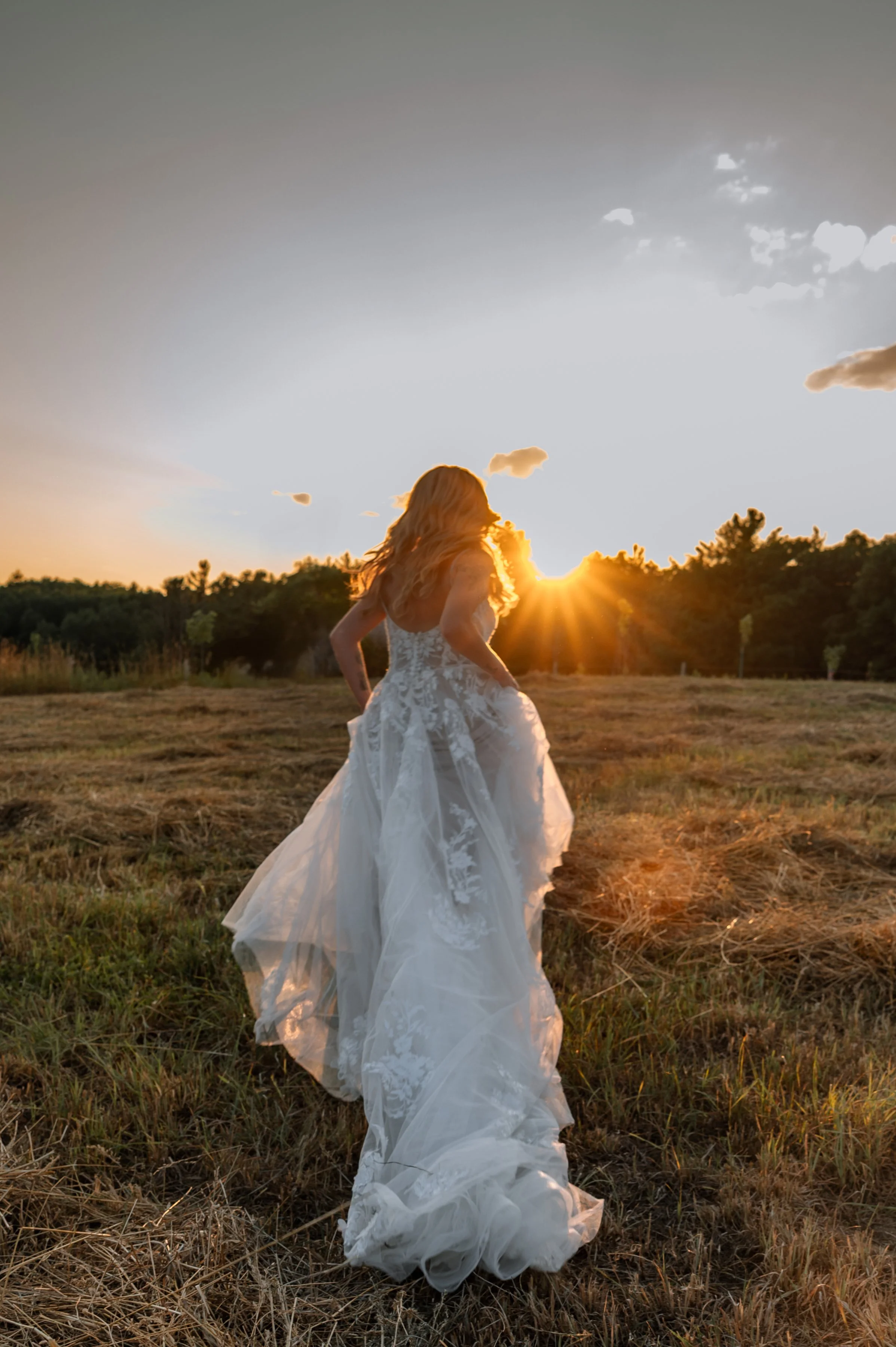 A bride running in a field toward the lowering sun of golden hour, during bridal portraits in York Region.
