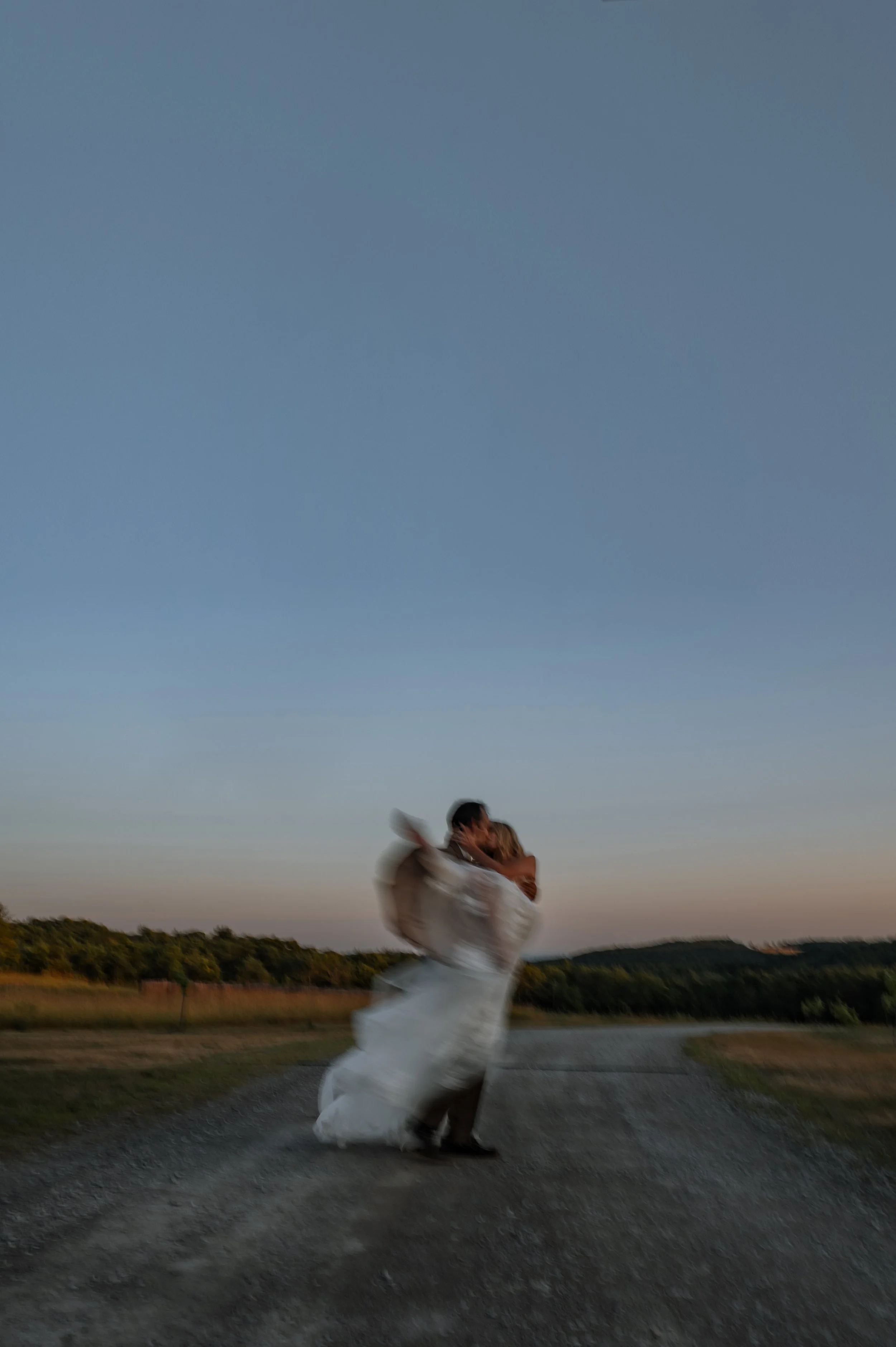 A blurry portrait at sundown of a groom holding his new wife and spinning in circles, during wedding portraits in the GTA.