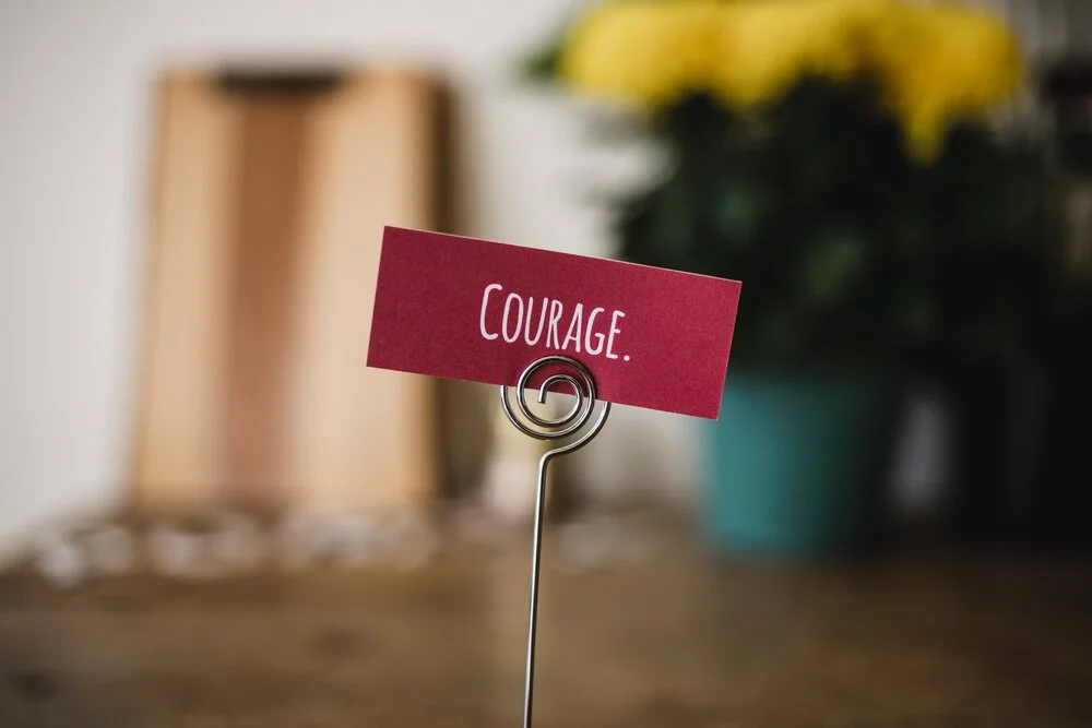 The word "courage" on a card being held up in a pacecard holder