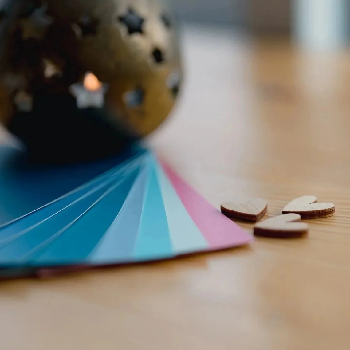 A tealight, little wooden hearts, and some paint swatches on a wood table