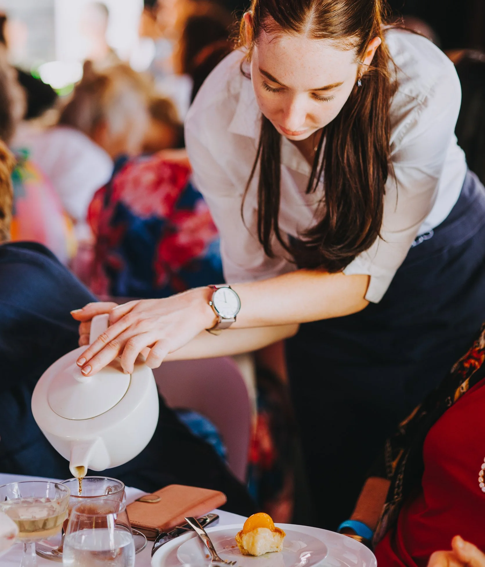 Michels waitress pouring tea from a teapot at a high tea