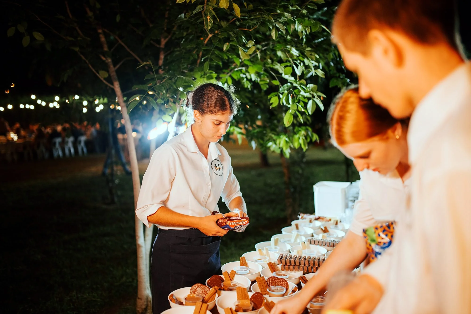 Michels waitstaff preparing canapés at an outdoor service point at night