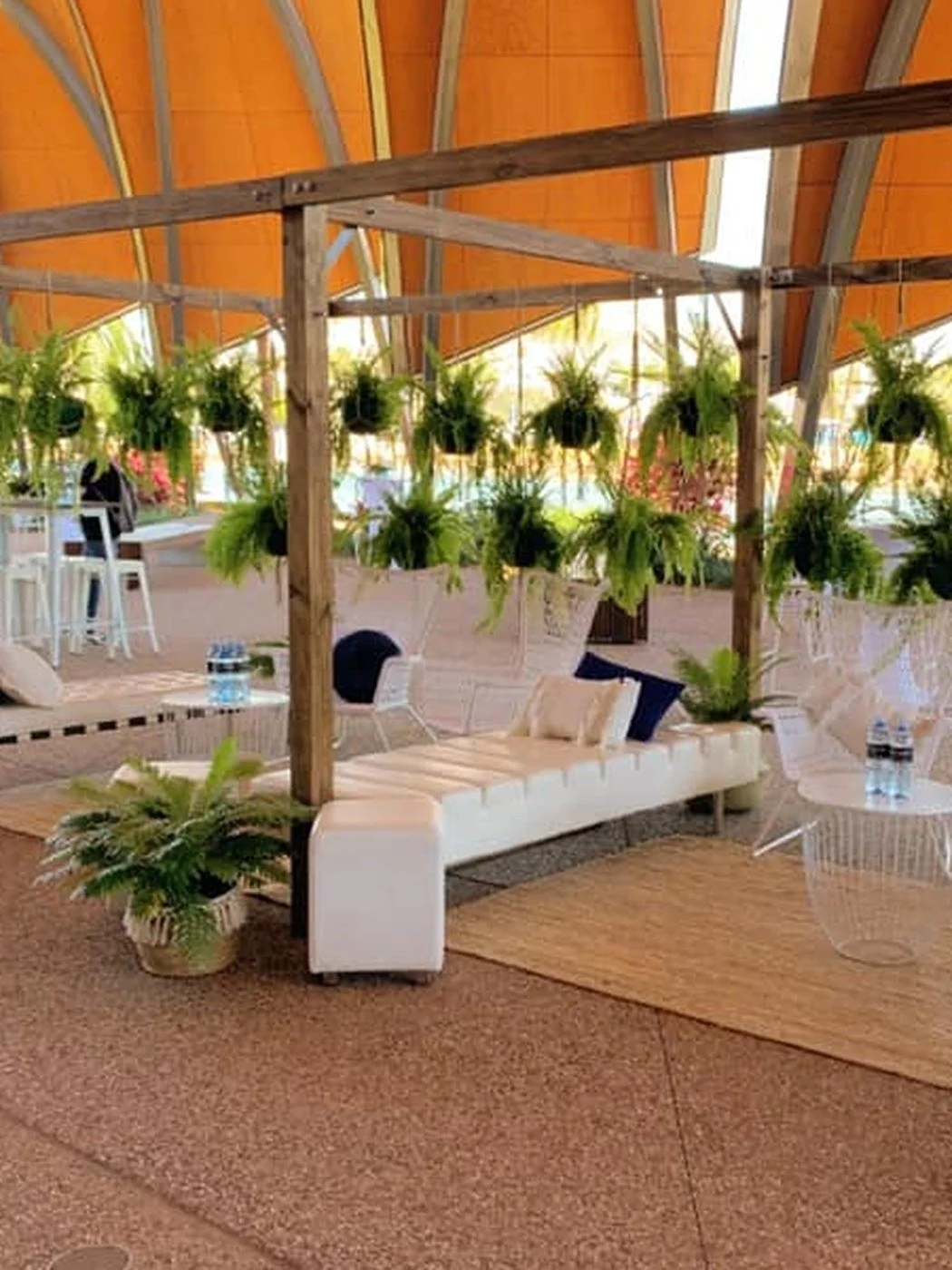 Conference breakout lounge styled by Michels with white lounges, hanging ferns and a timber pergola
