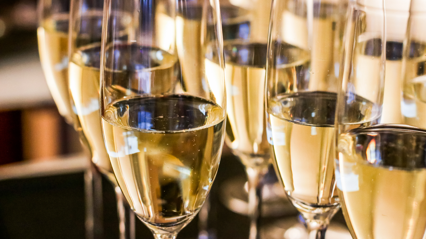Multiple glasses of champagne toast with golden liquid, close-up shot.