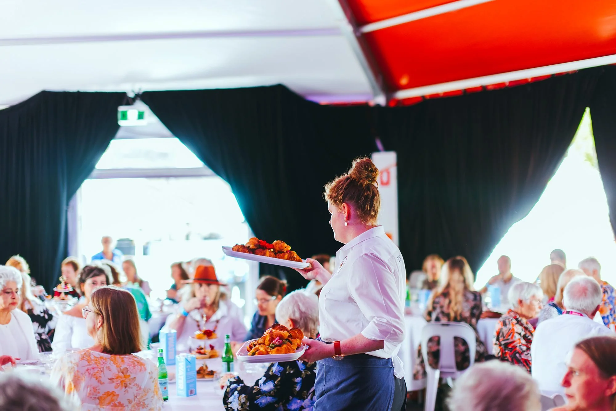 Michels waitress carrying a platter of food through a corporate event marquee
