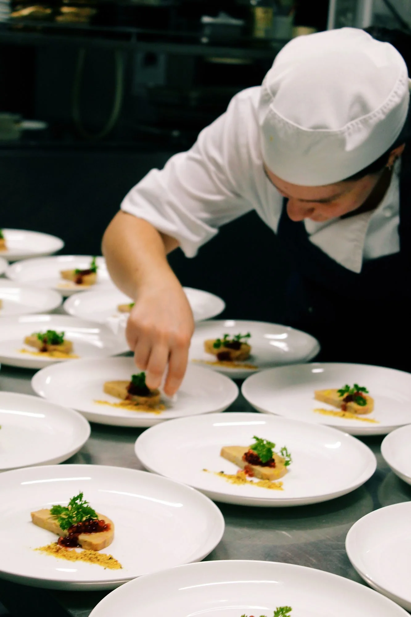 Michels chef finishing rows of plated dishes in the kitchen