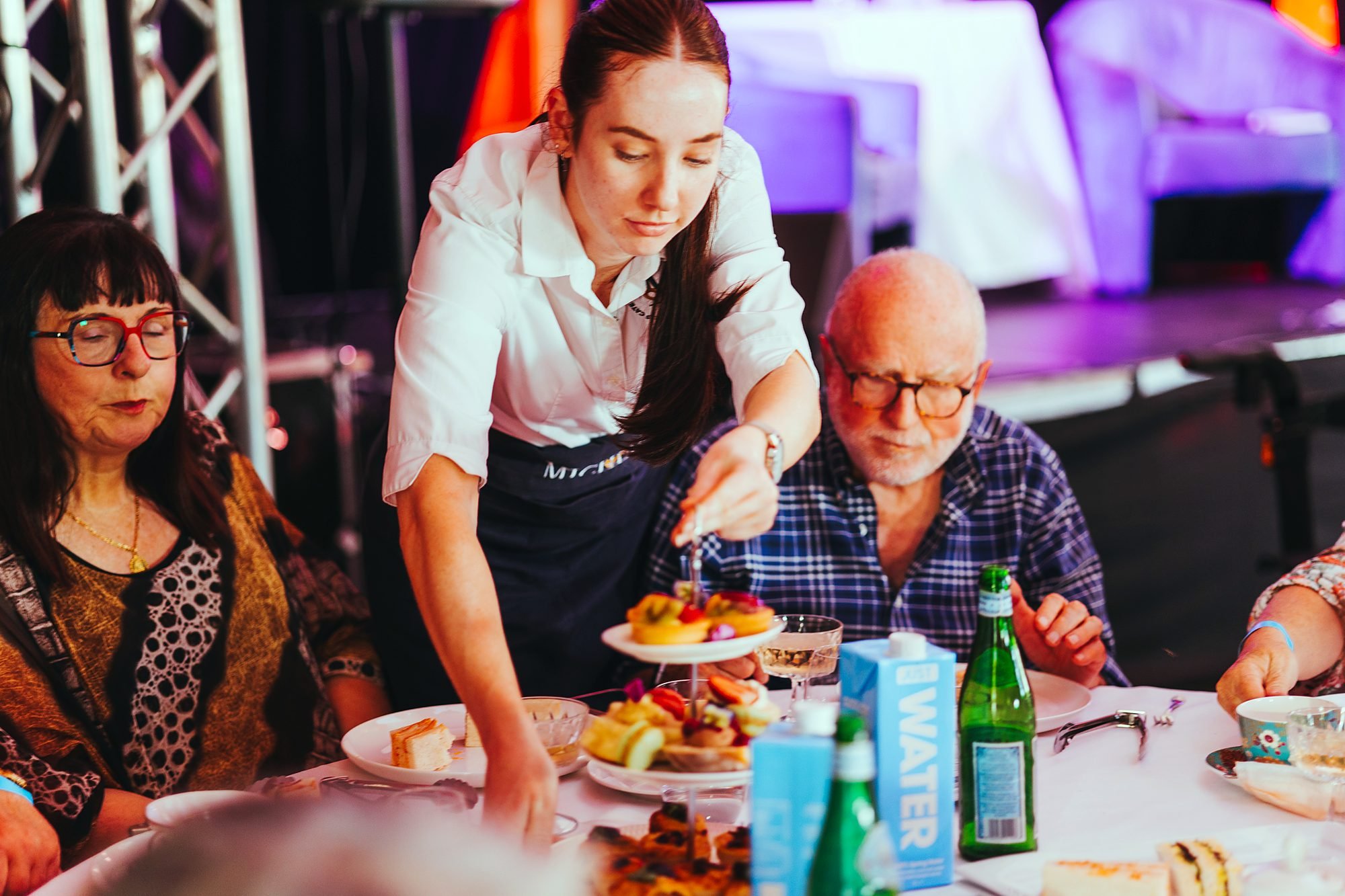 Michels waitstaff serving a high tea stand to guests at a large event