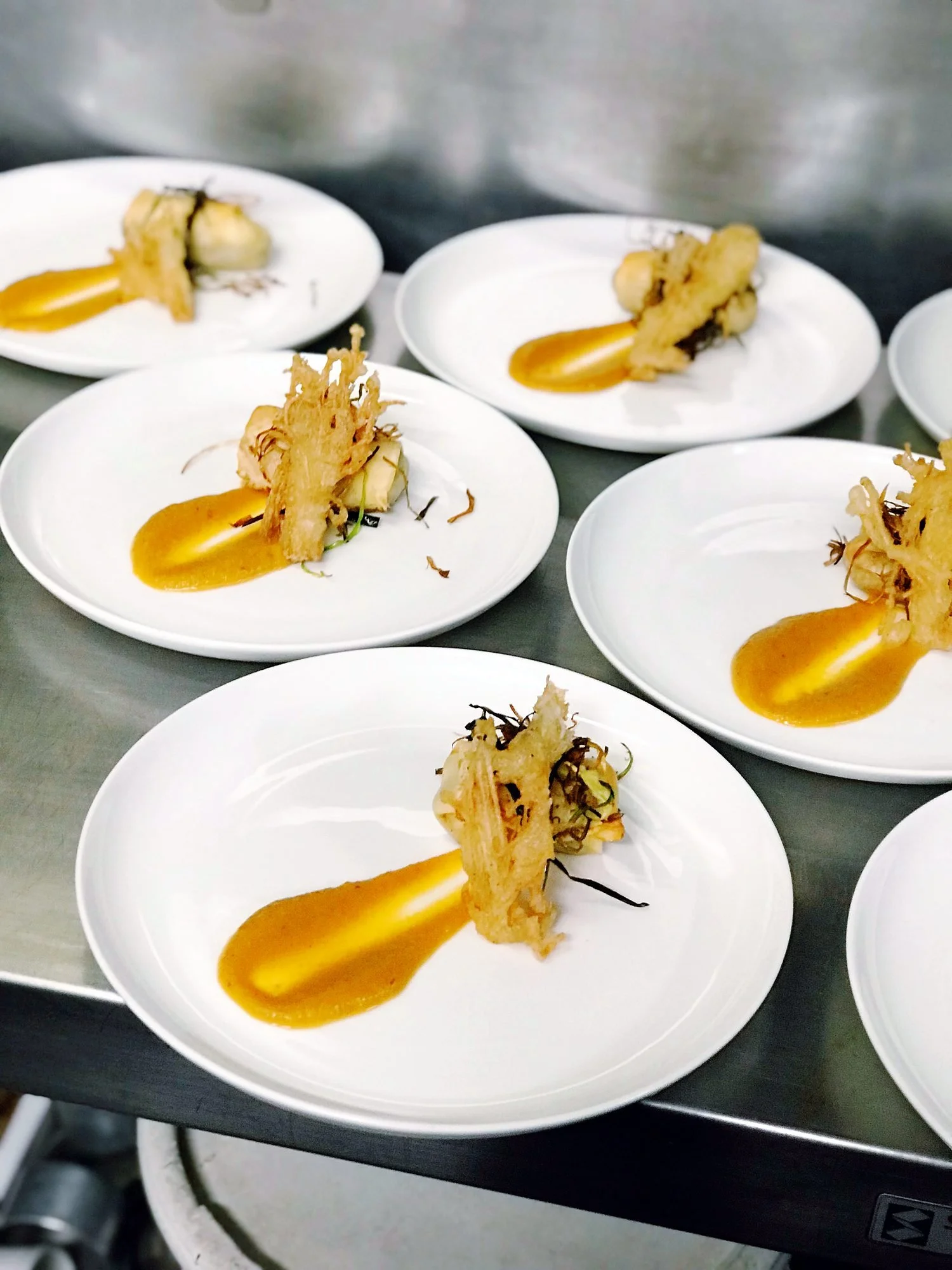 Plated entrées with a bright orange purée, ready to serve at a Michels event