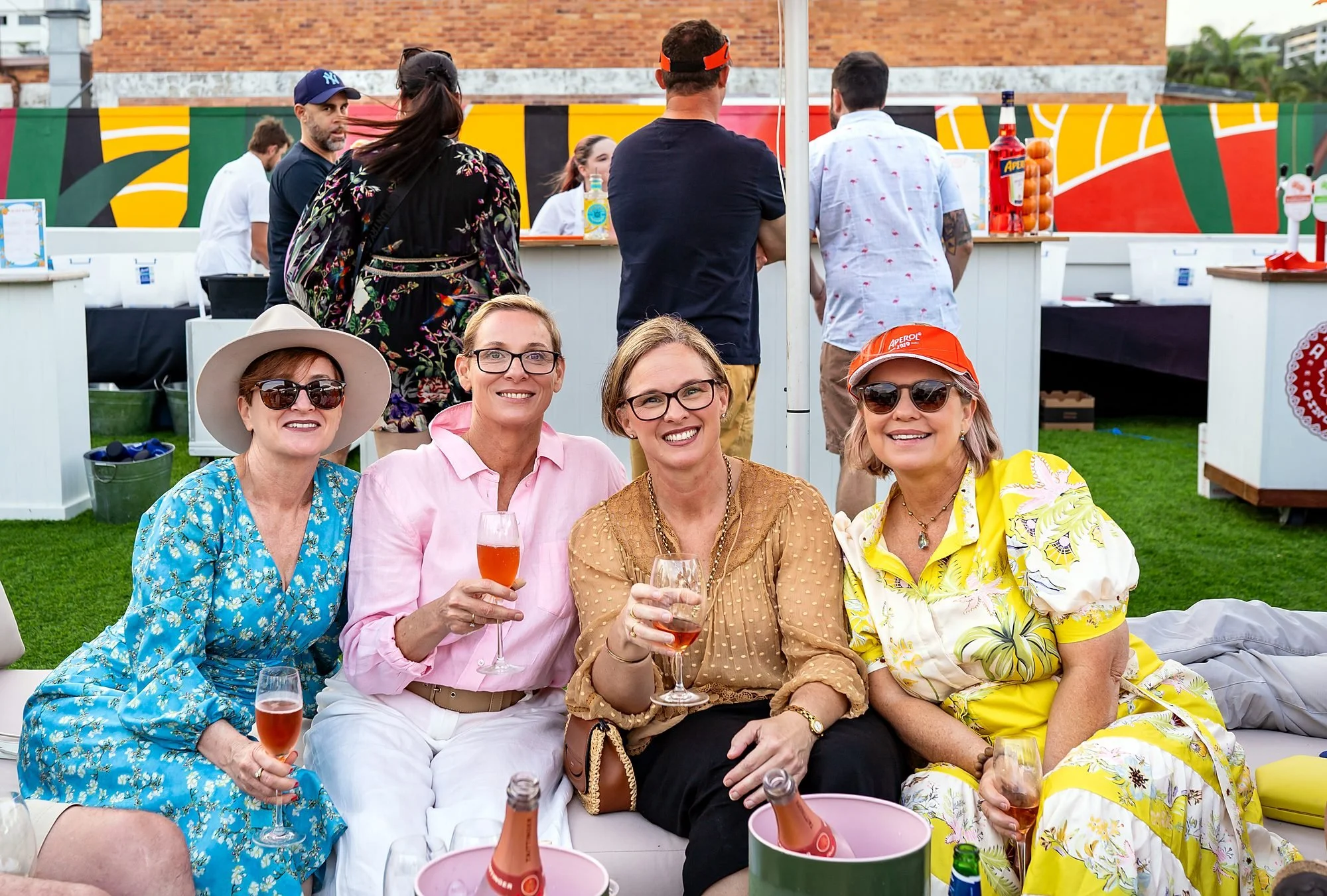 Four friends smiling with glasses of rosé at an outdoor party