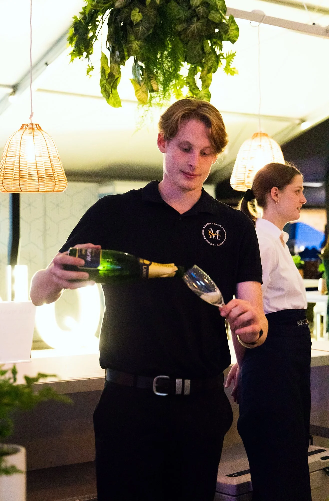 Michels waiter pouring champagne for guests at a wedding reception