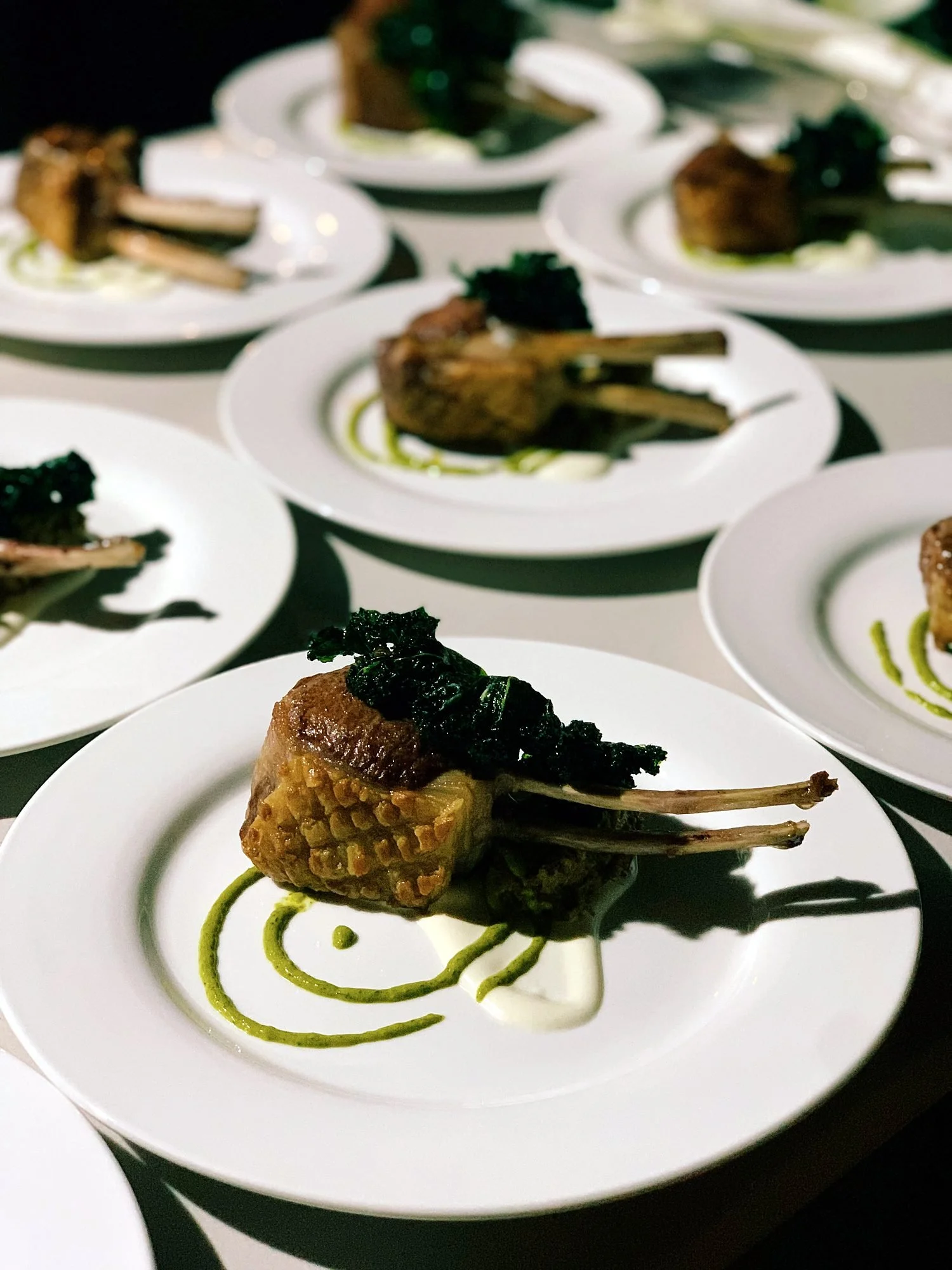 Rows of plated lamb cutlet mains ready to leave the kitchen