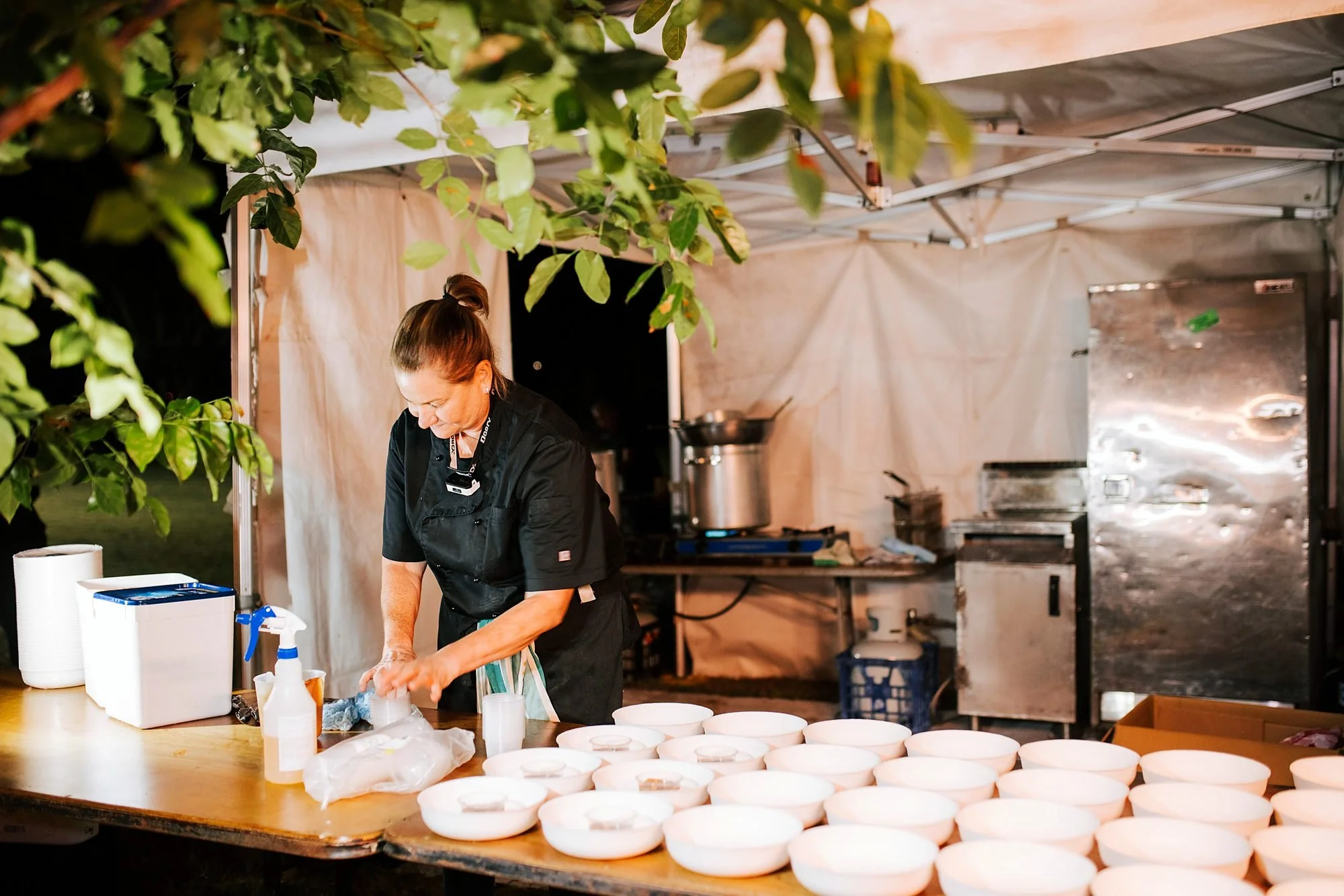 Michels chef preparing bowls at an outdoor event kitchen marquee
