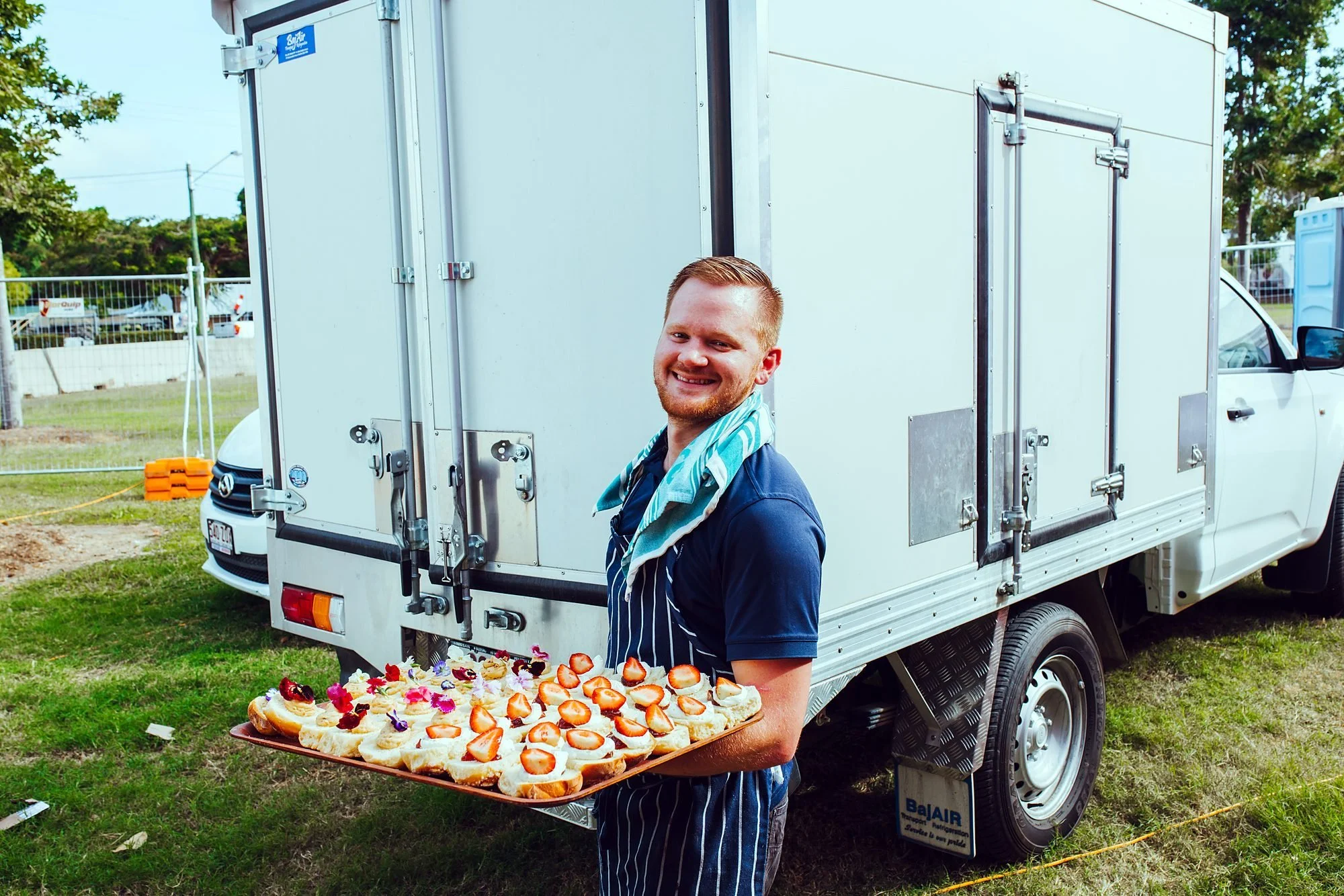 Michels chef with a platter beside the refrigerated delivery van