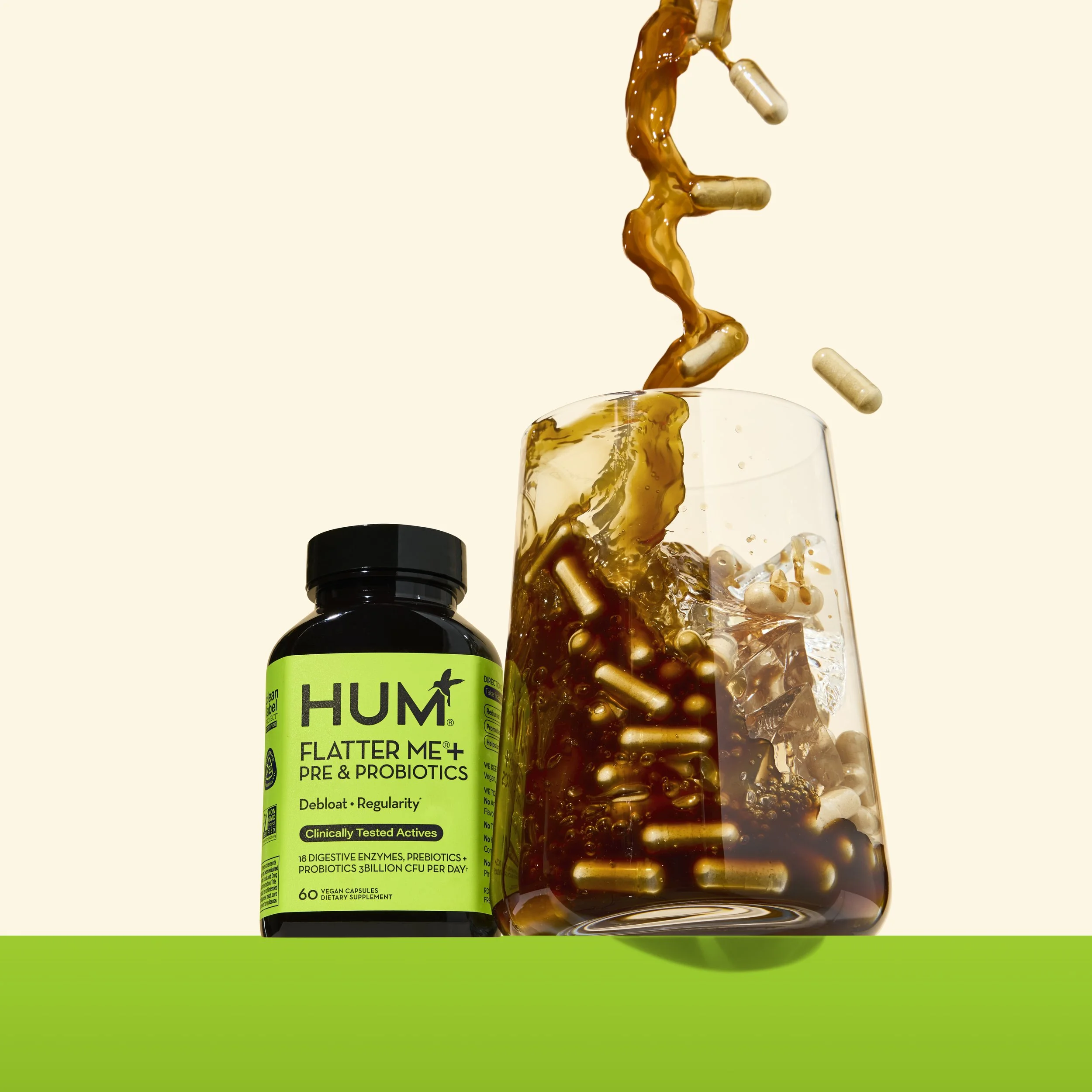 Set Designer, Prop Stylist DANA KAPUSTIN styled this fun brightly colored scene for Hum Nutrition's Flatter Me. Bright neon green bottle sits onto of a green block. Ice coffee pouring over a glass of ice with pills splashing into glass. 