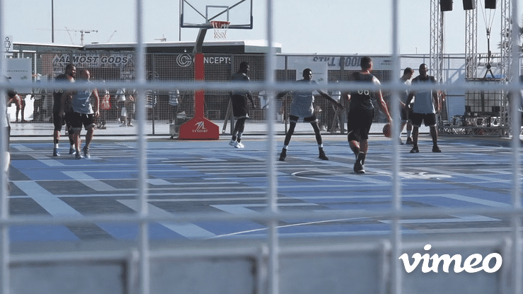 Teenagers playing basketball on an outdoor urban court during the day.