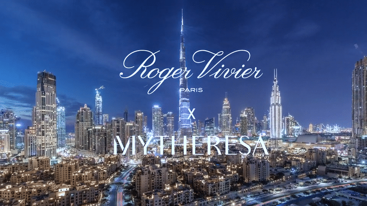 Nighttime view of a city skyline with tall illuminated buildings, including the Burj Khalifa, against a dark sky, with text overlay reading 'Roger Vivier Paris x MYTHERESA'.