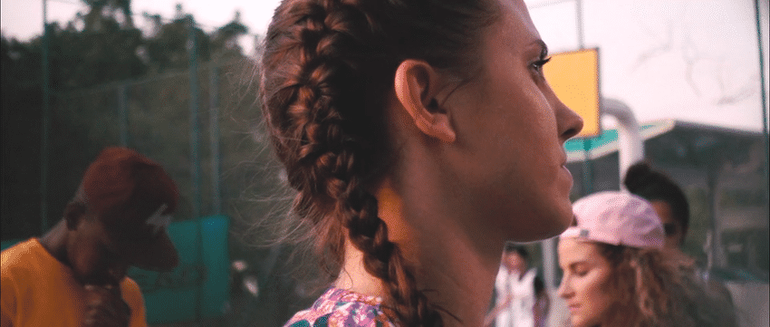 A group of young women with braided and curly hair standing outdoors on a cloudy day.