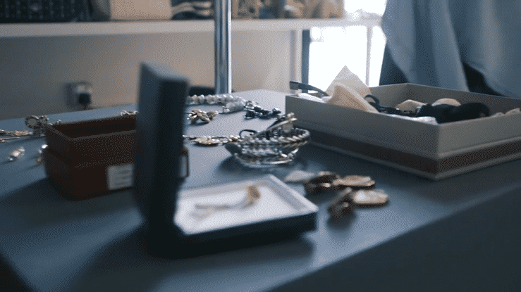 Jewelry displayed on a table with trays and a box, including bracelets, rings, and earrings.
