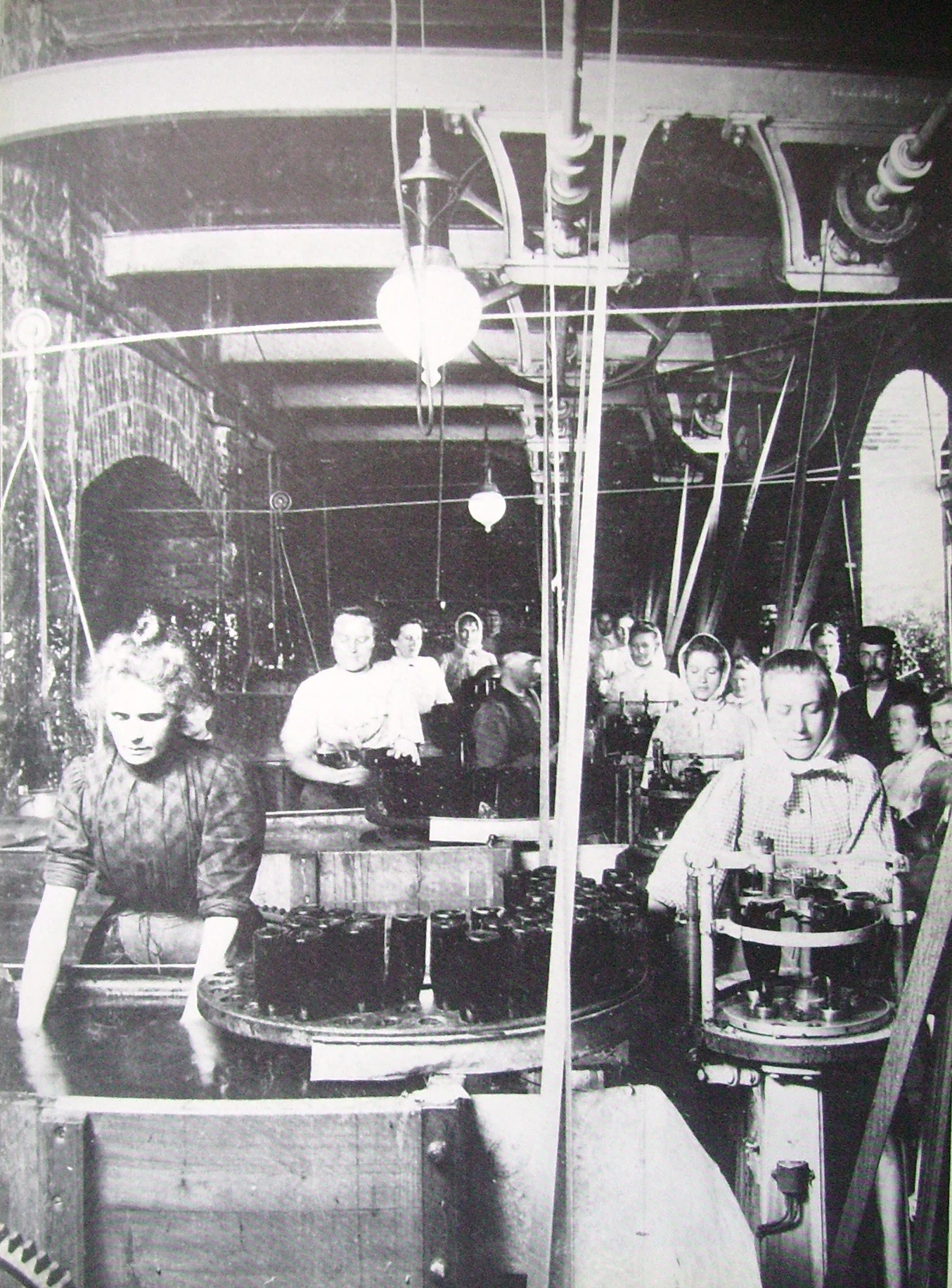 Svartvitt foto av bryggerskor som arbetar vid olika flaskstationer i fabrik.