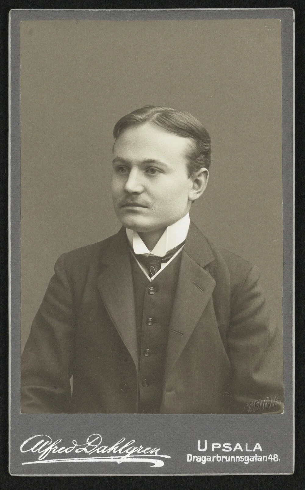 Porträtt på John Landquist, han har kostym, bakåtkammat hår och en tunn mustasch.