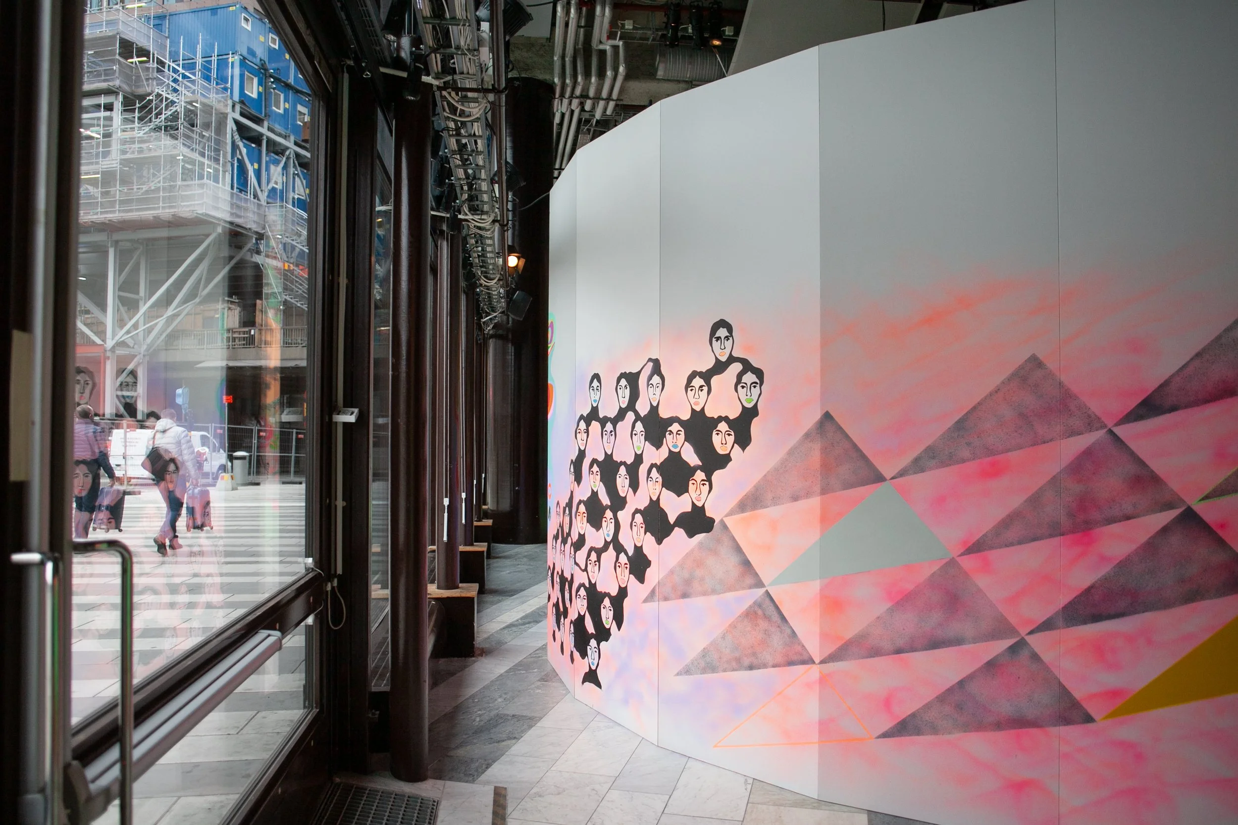 En rundad vägg med målningar av kvinnor och Sergels torg.