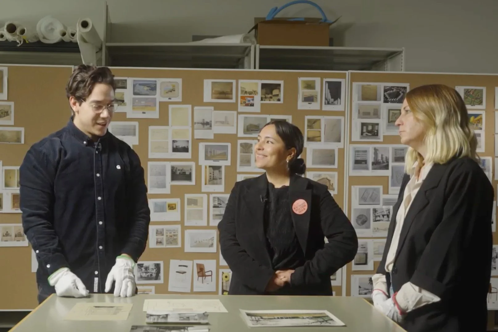 Max Ahrent, Frida Melin och Camilla Burvall Terán står framför en skärm och bakom ett bord under visningen i arkivet på ArkDes.