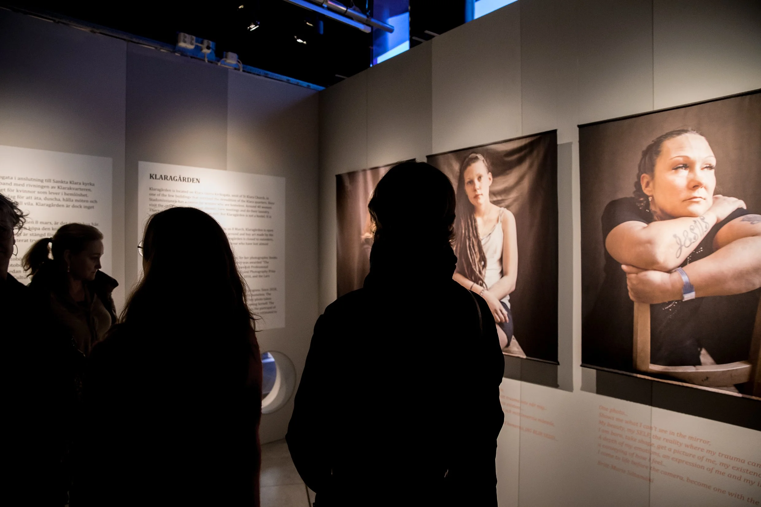 Porträtt av kvinnor i utställningen, framför dem siluetter av besökare.