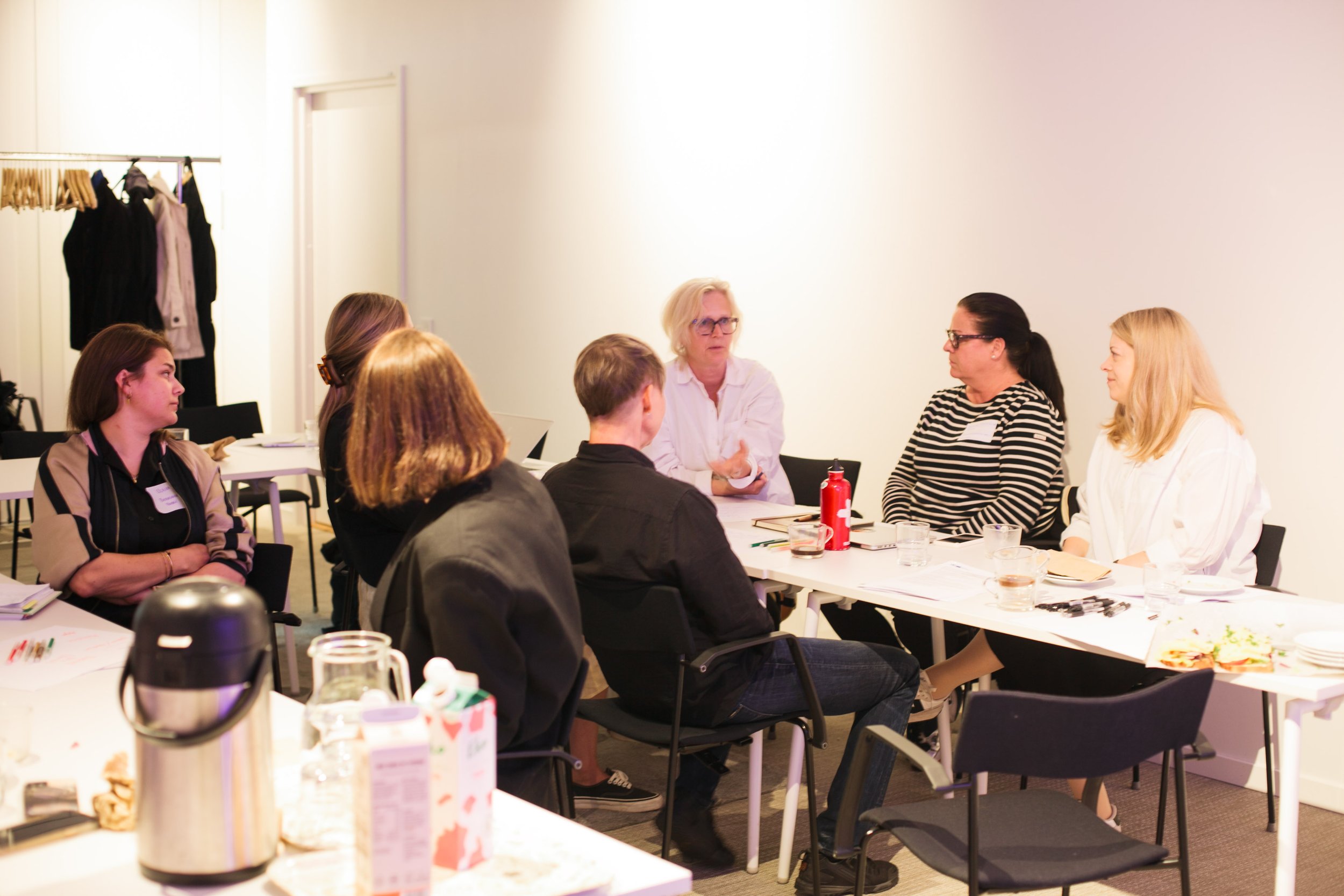 Personer sitter och diskuterar vid bord.